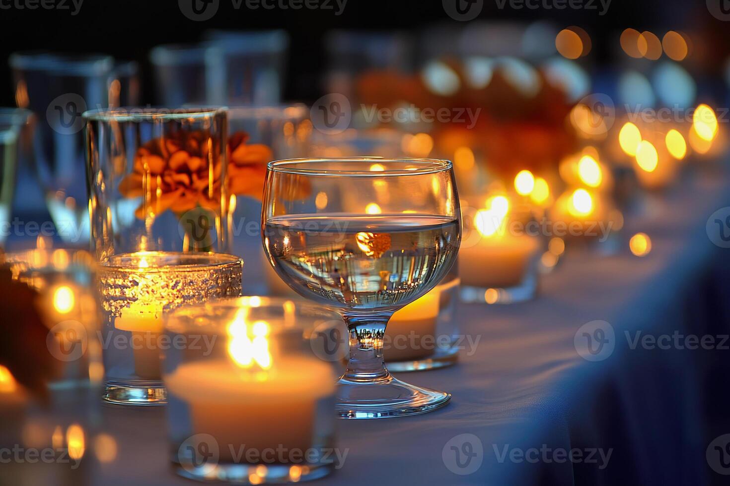 Soft glow of candles illuminates glasses and flowers on a table for a cozy evening event photo