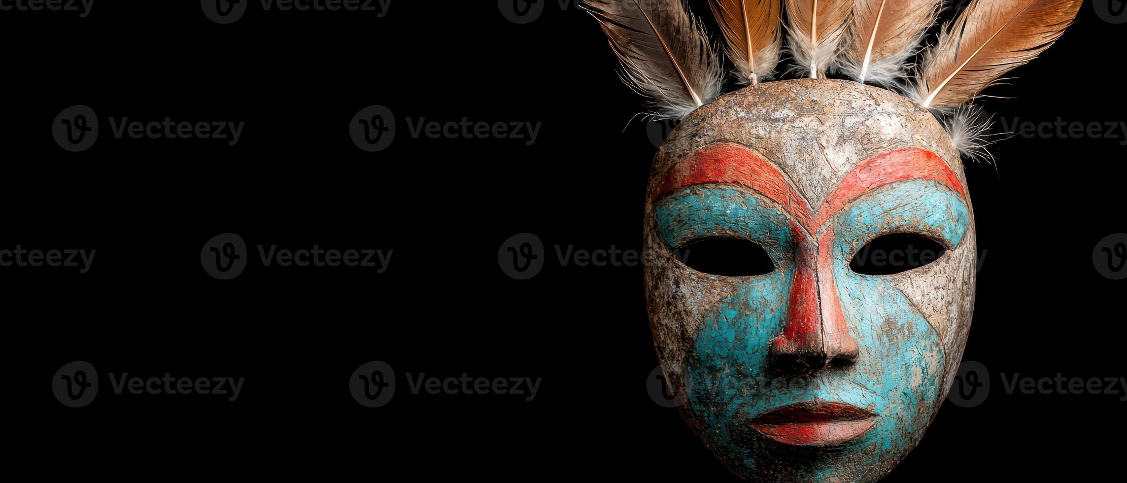 Colorful tribal mask with feathers against a dark background photo