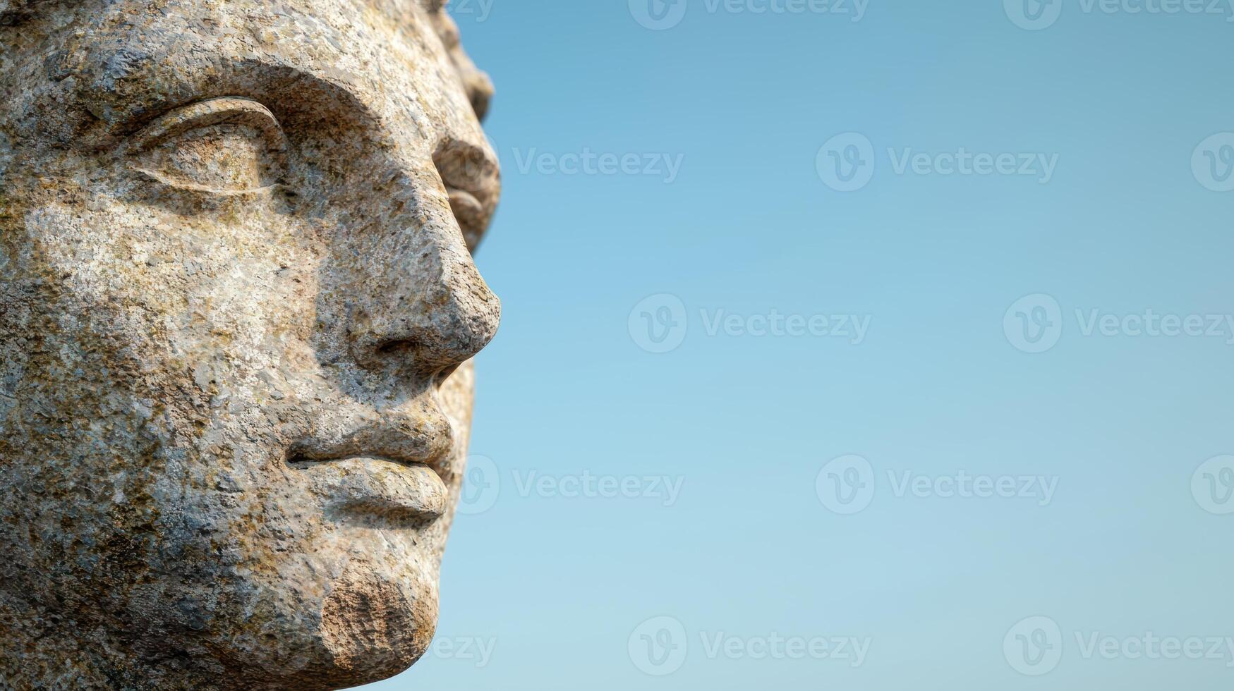 Close up of a stone face against a blue sky photo