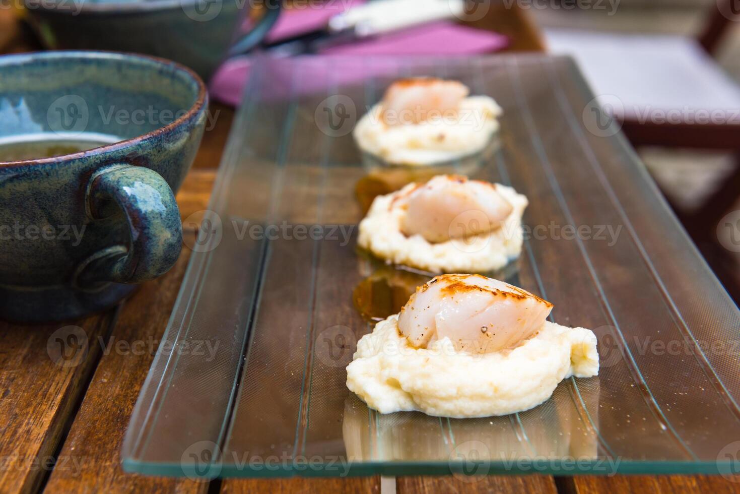Close up of pan seared sea scallops and a cup of cider photo