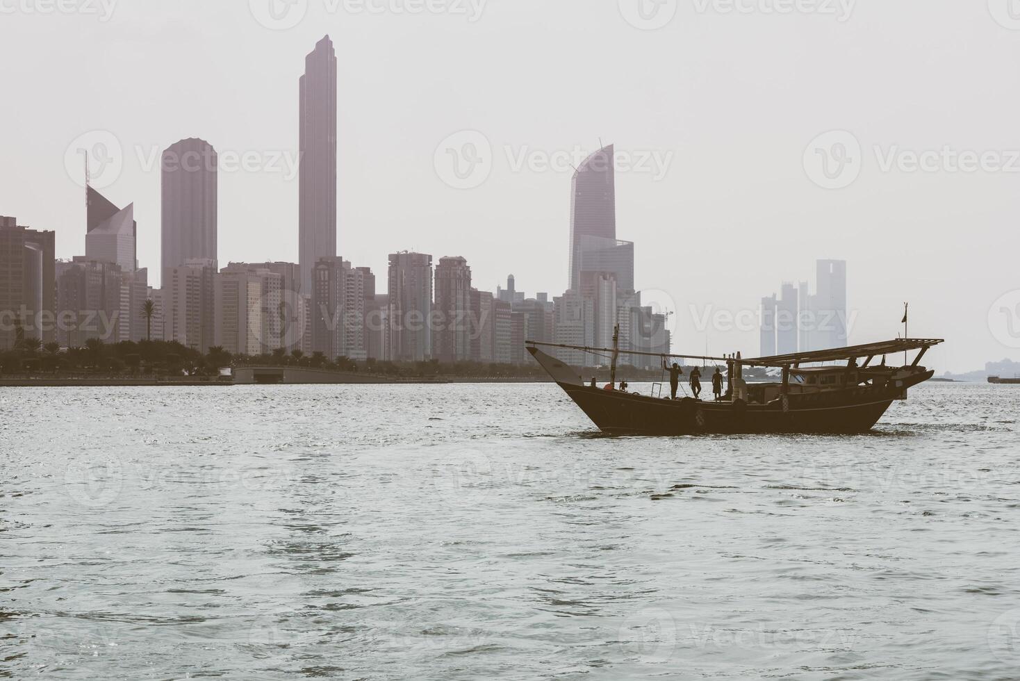 Abu Dhabi buildings skyline with old fishing boat photo