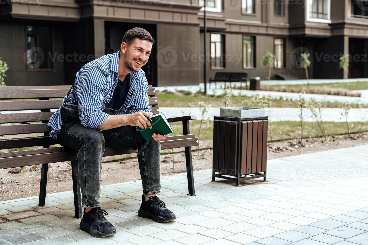 A person writes in a notebook while sitting on a park bench photo