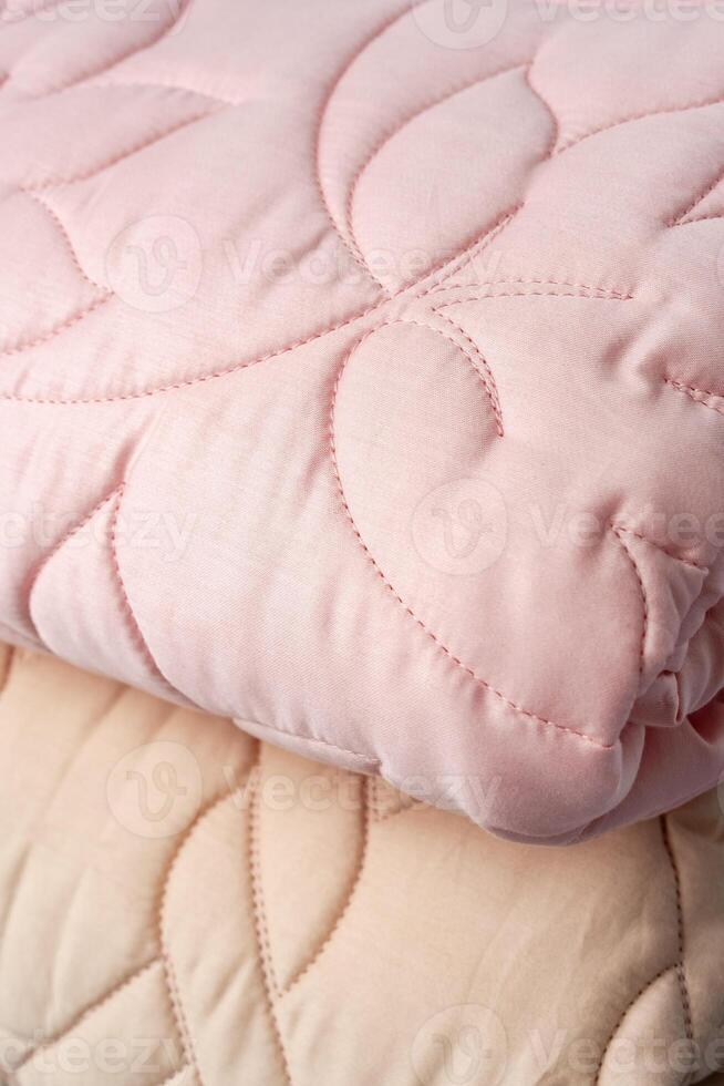 Stacked Pink And Peach Quilted Blankets On A Gray Bed photo