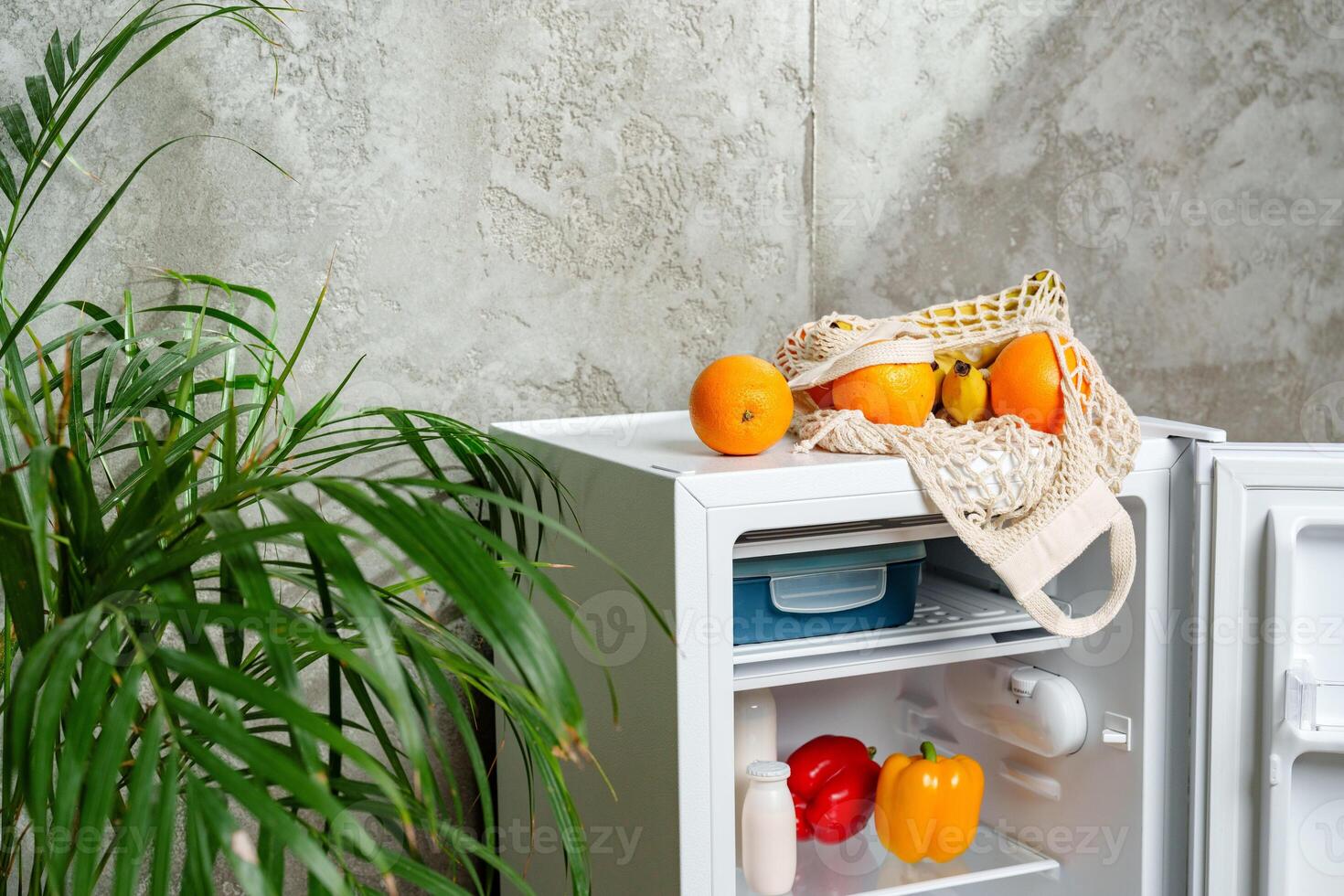 Open Refrigerator With Fresh Produce and Mesh Bag in Kitchen photo