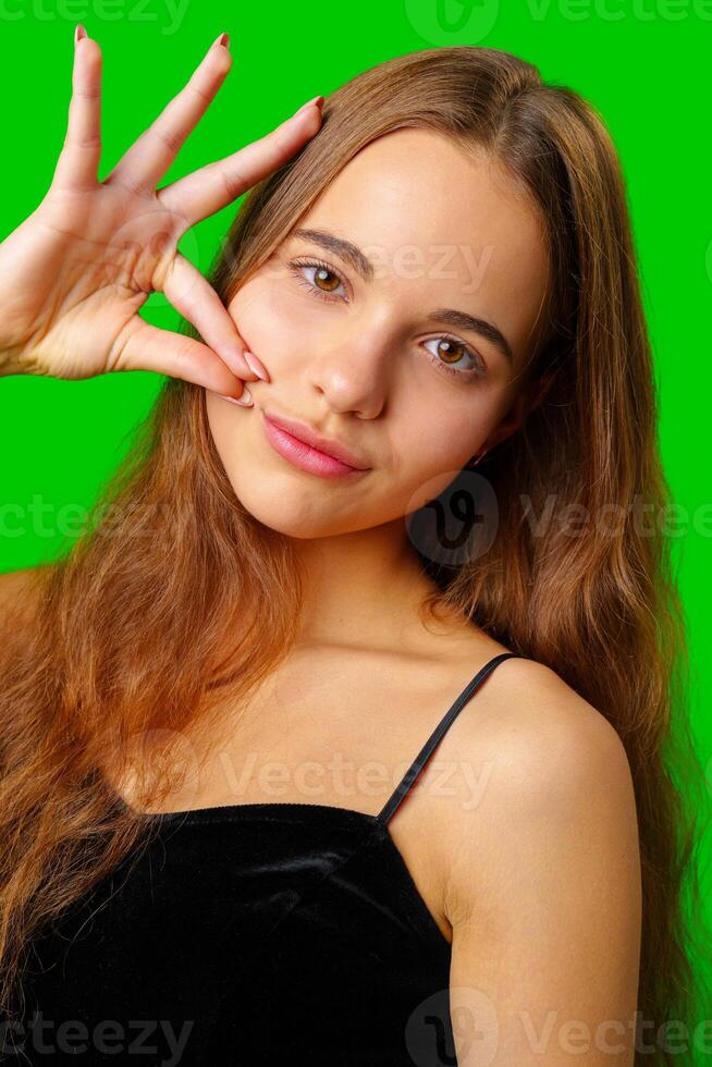 Young Woman Making a Hush Gesture against green background photo