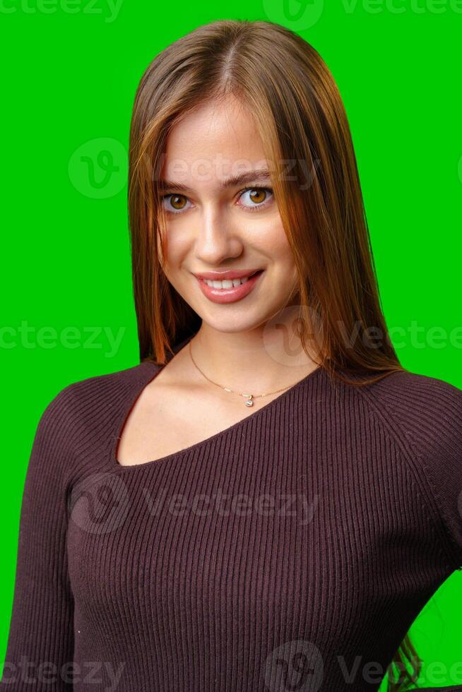 Young Woman Smiling In A Brown Sweater Against Green Screen photo
