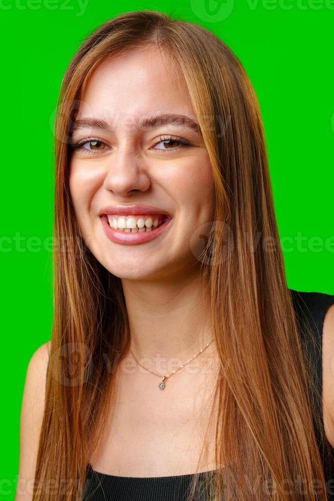 Young Woman Smiling With Long Brown Hair Against Green Screen photo