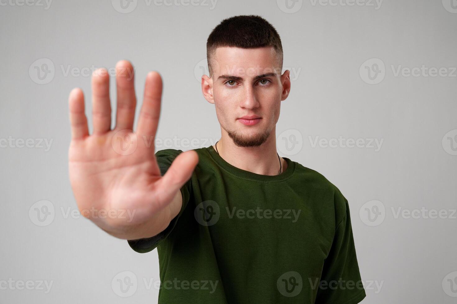 Young Man Holding Up Hand in Stop Gesture Against Grey Background photo
