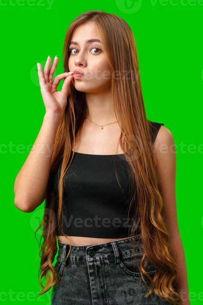 Young Woman With Long Brown Hair Makes a Shushing Gesture in Front of a Green Screen photo