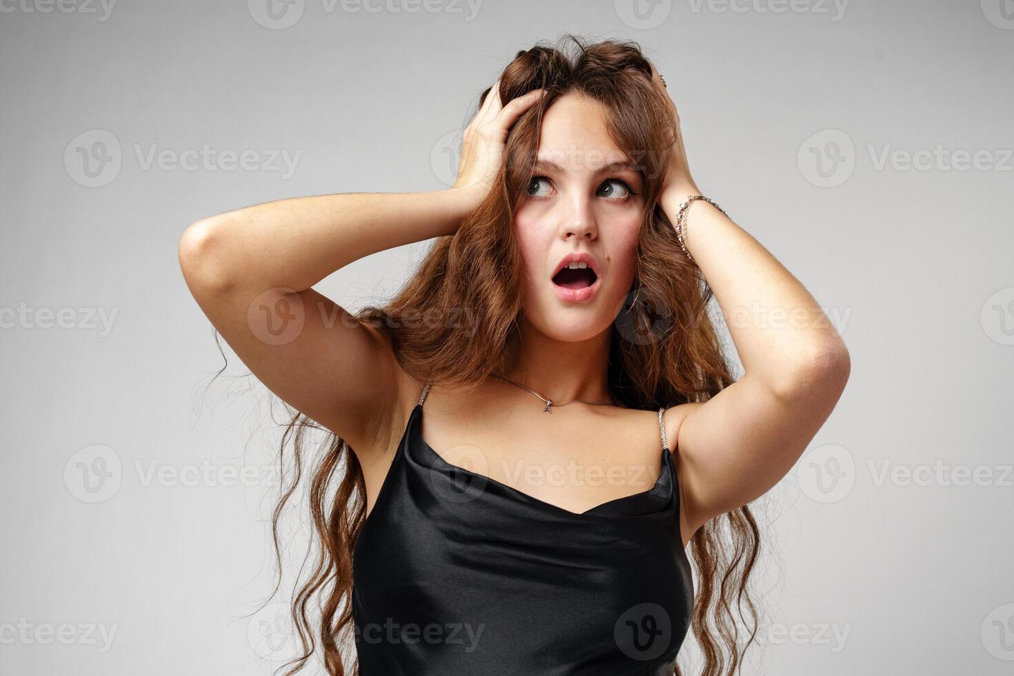 Young Woman in Black Slip Dress Looks Shocked in Studio Portrait photo