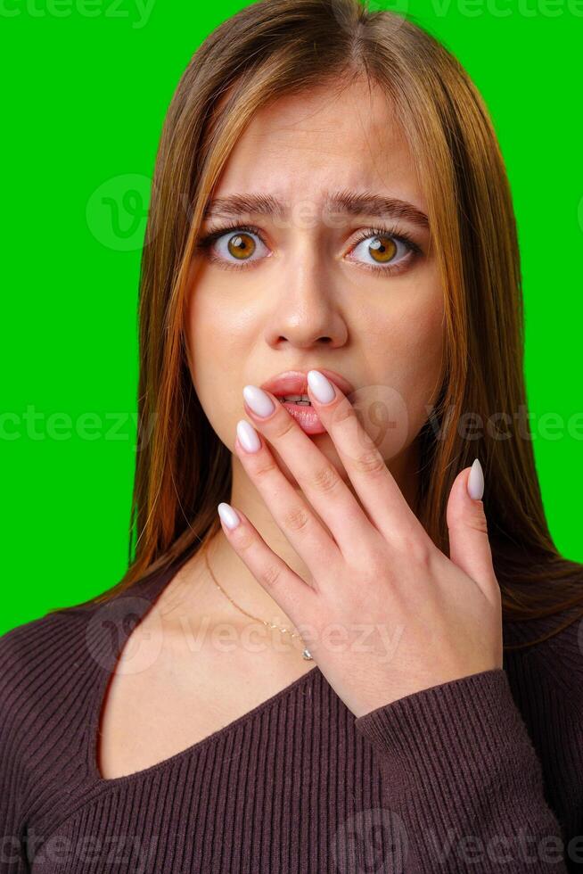 Woman Covering Mouth With Hand While Looking Surprised Against Green Screen photo