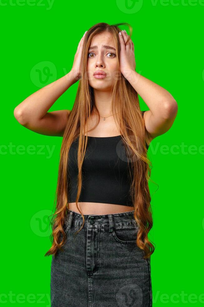 Young Woman With Long Brown Hair Holding Her Head In Frustration On Green Screen photo