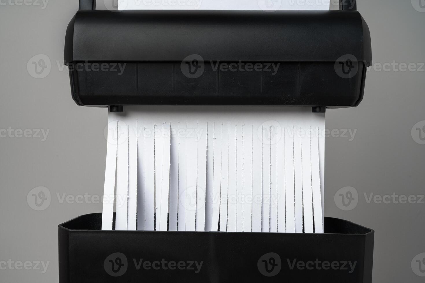 Black paper shredder cutting paper on gray background photo
