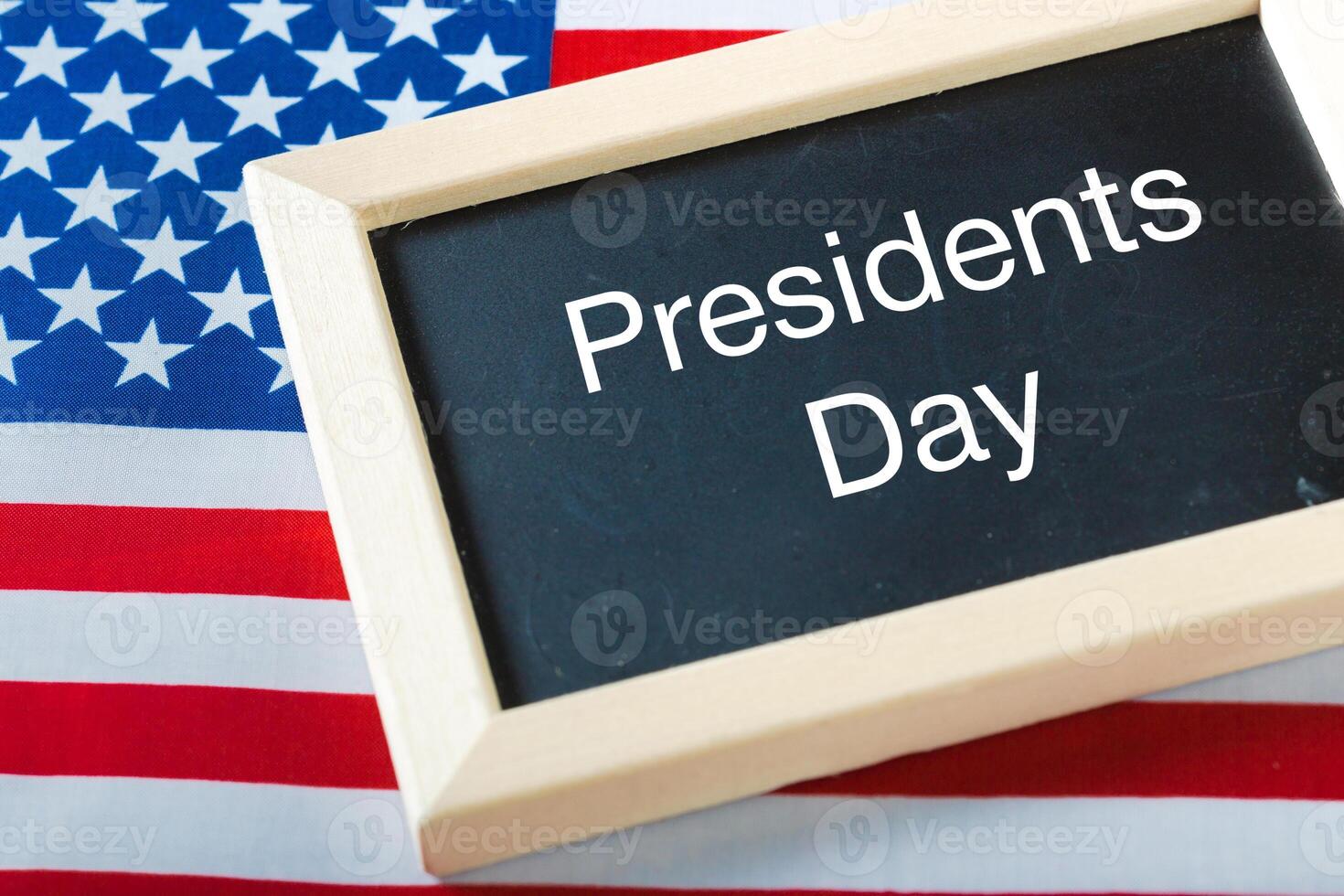 the text happy presidents day written in a chalkboard and a flag of the United States photo