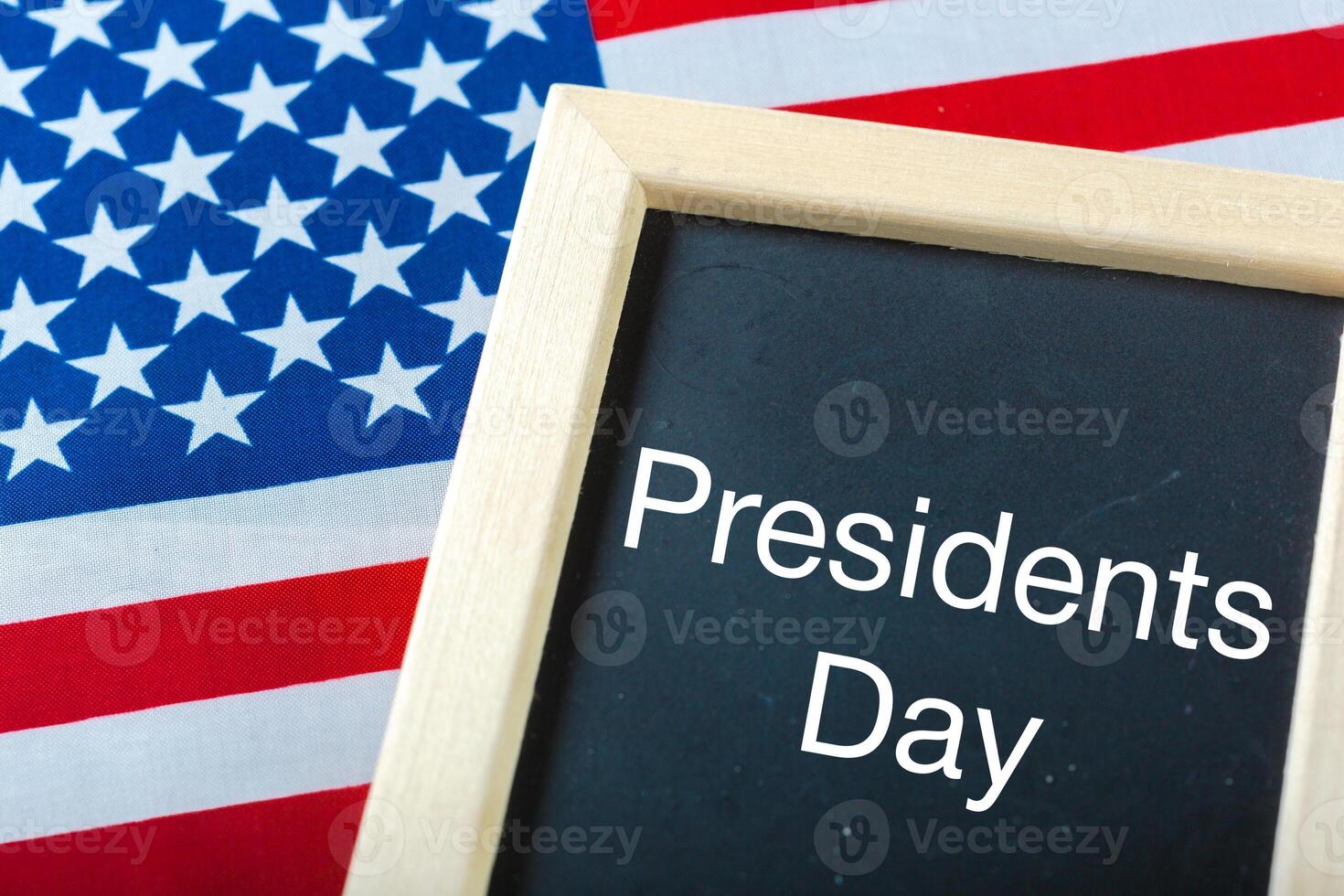 the text happy presidents day written in a chalkboard and a flag of the United States photo