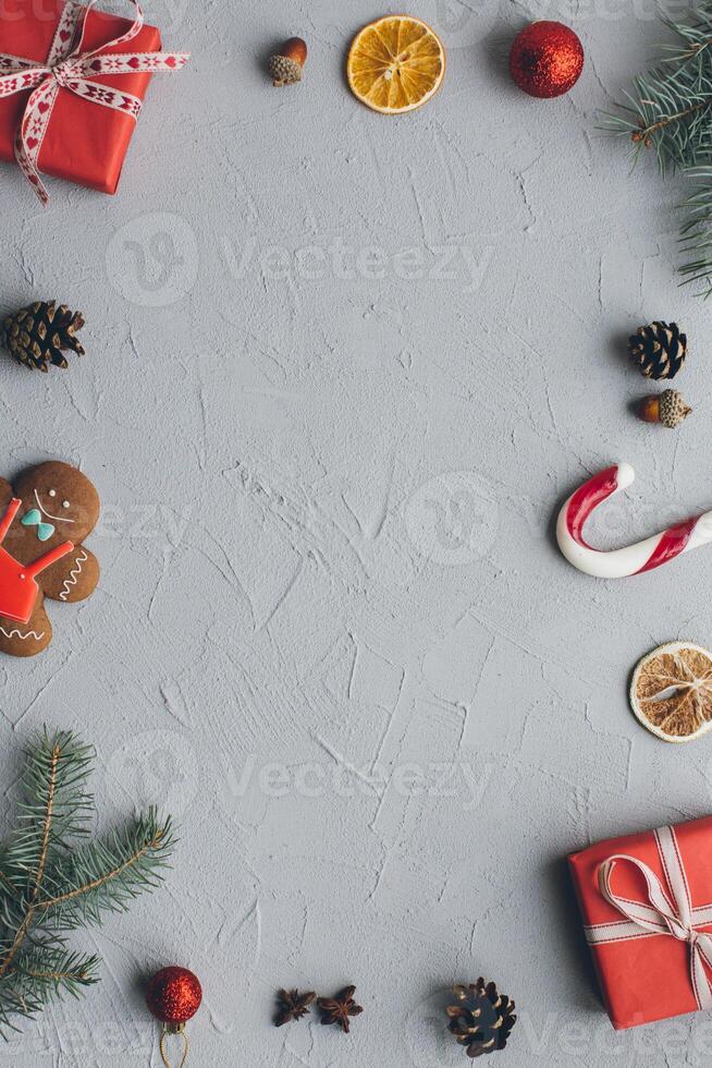 Christmas composition. Gifts, pine cones, fir branches, candy, gingerbread man, spices and other decorations on vintage gray background. Flat lay, top view. photo