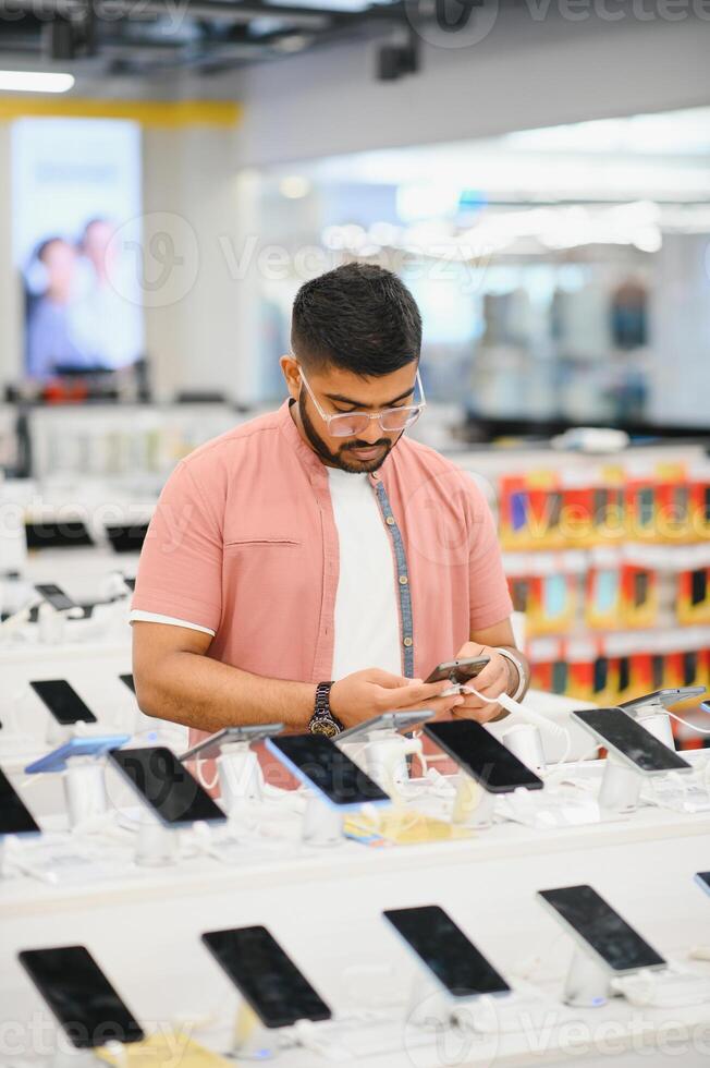 Indian man customer buyer at mobile phone store choose his new smartphone photo