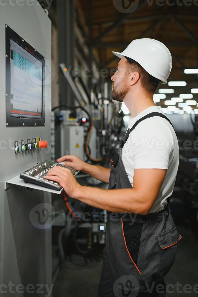 Factory male bearded worker is programming a CNC milling machine with copy space photo