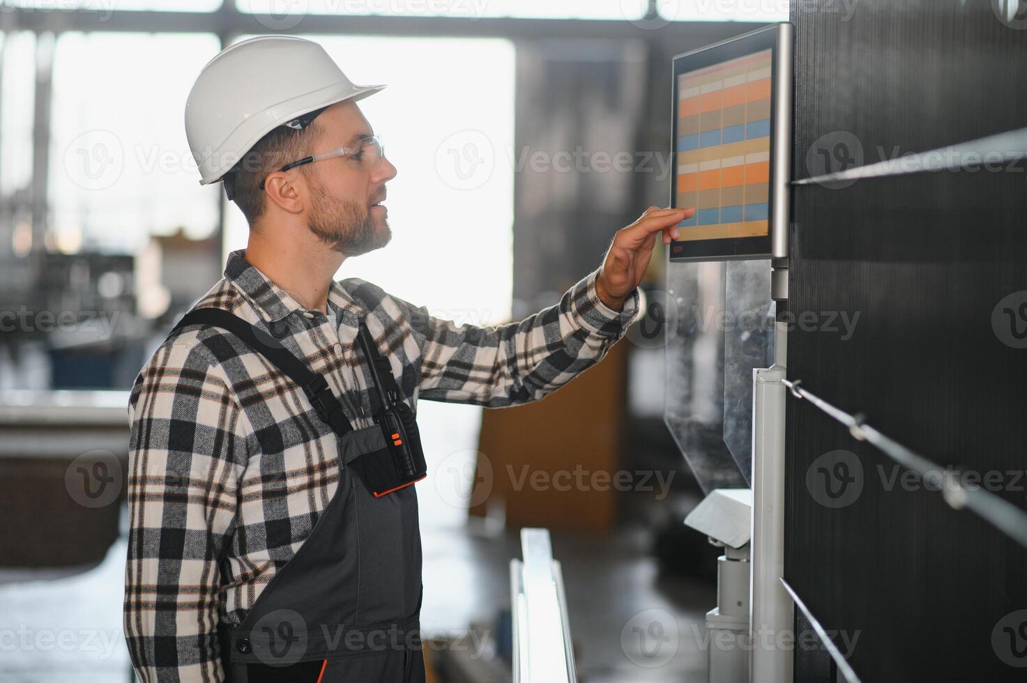 Factory male bearded worker is programming a CNC milling machine with copy space photo