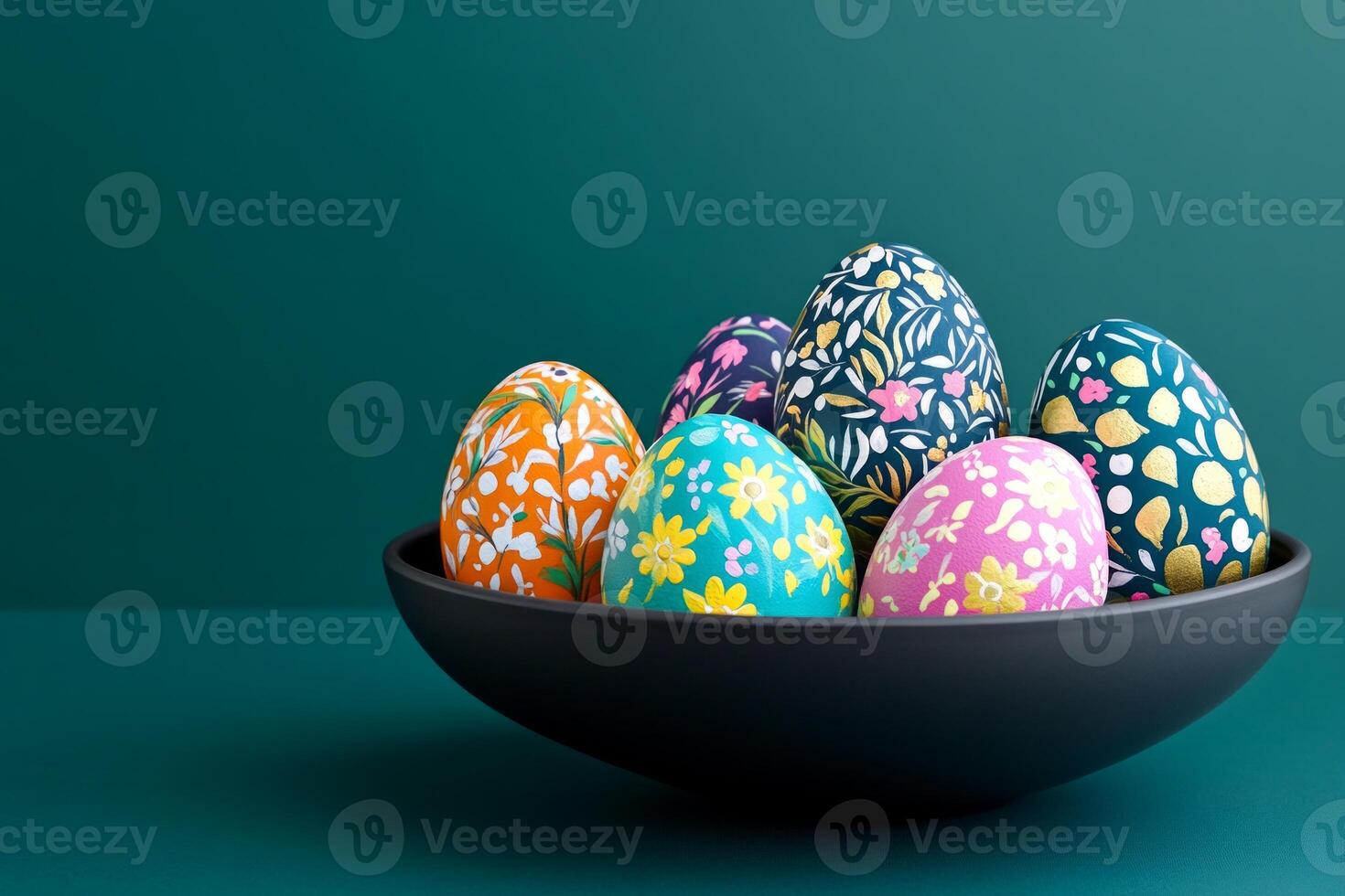 Colorful hand-painted Easter eggs with folk art patterns in a dark bowl on a deep teal backdrop photo