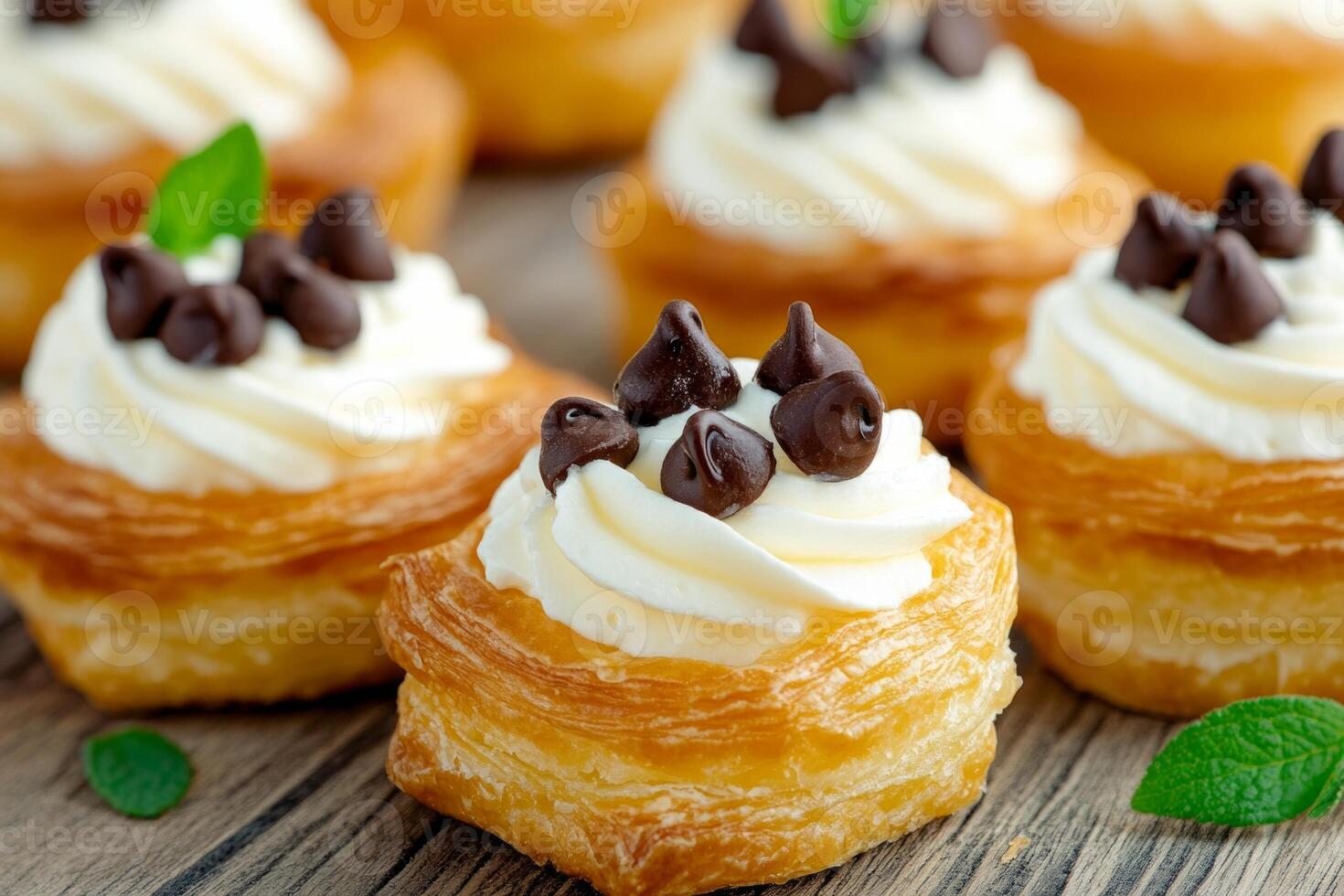 Delicious mini puff pastries topped with cream cheese and chocolate chips on a rustic wooden surface photo