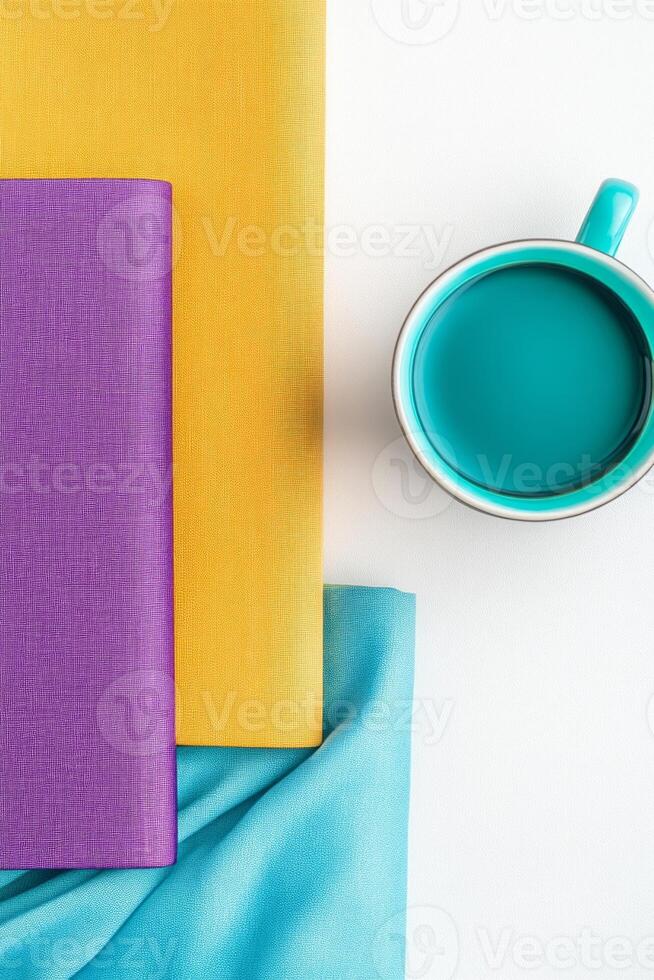 Vibrant workspace flat lay featuring colorful notebooks and a turquoise coffee cup on a clean white desk photo