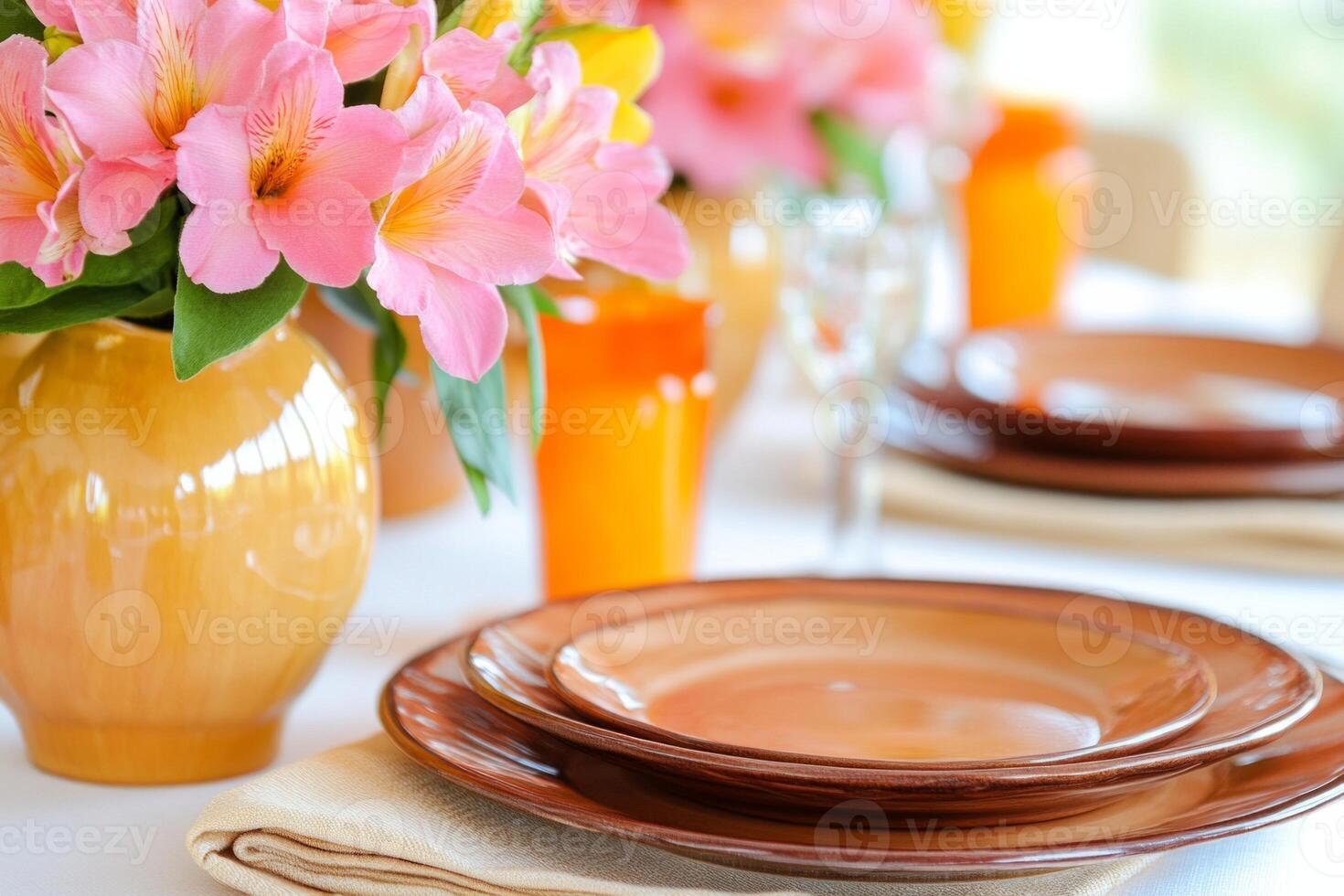Elegant dining table setup featuring brown plates, pink flowers, and vibrant candles for a special occasion photo