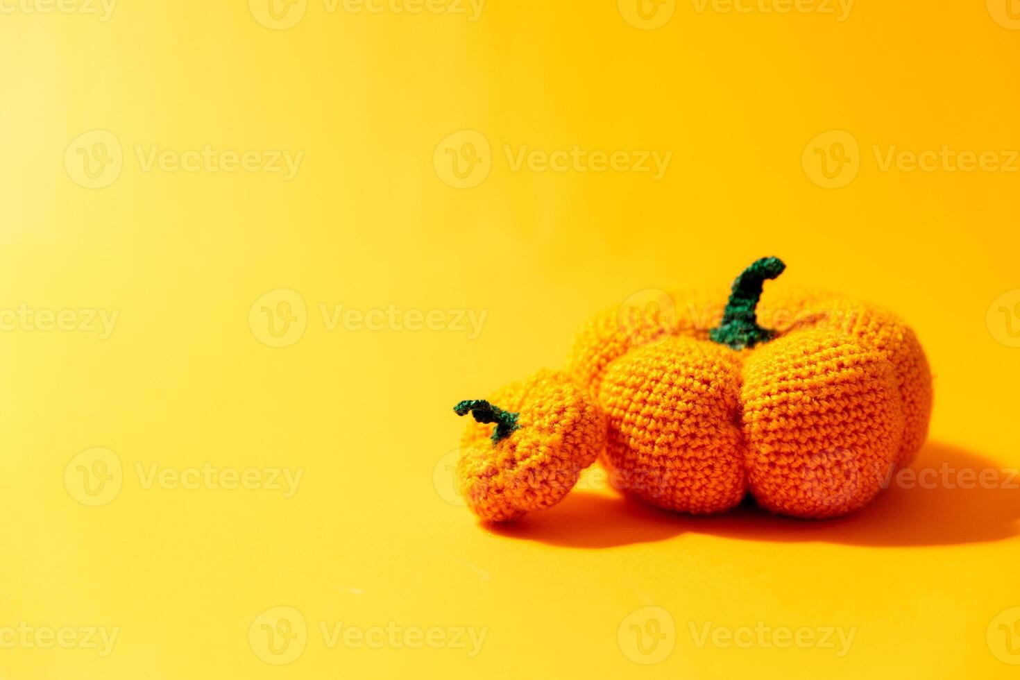 Knitted toy baby pumpkins on yellow background photo