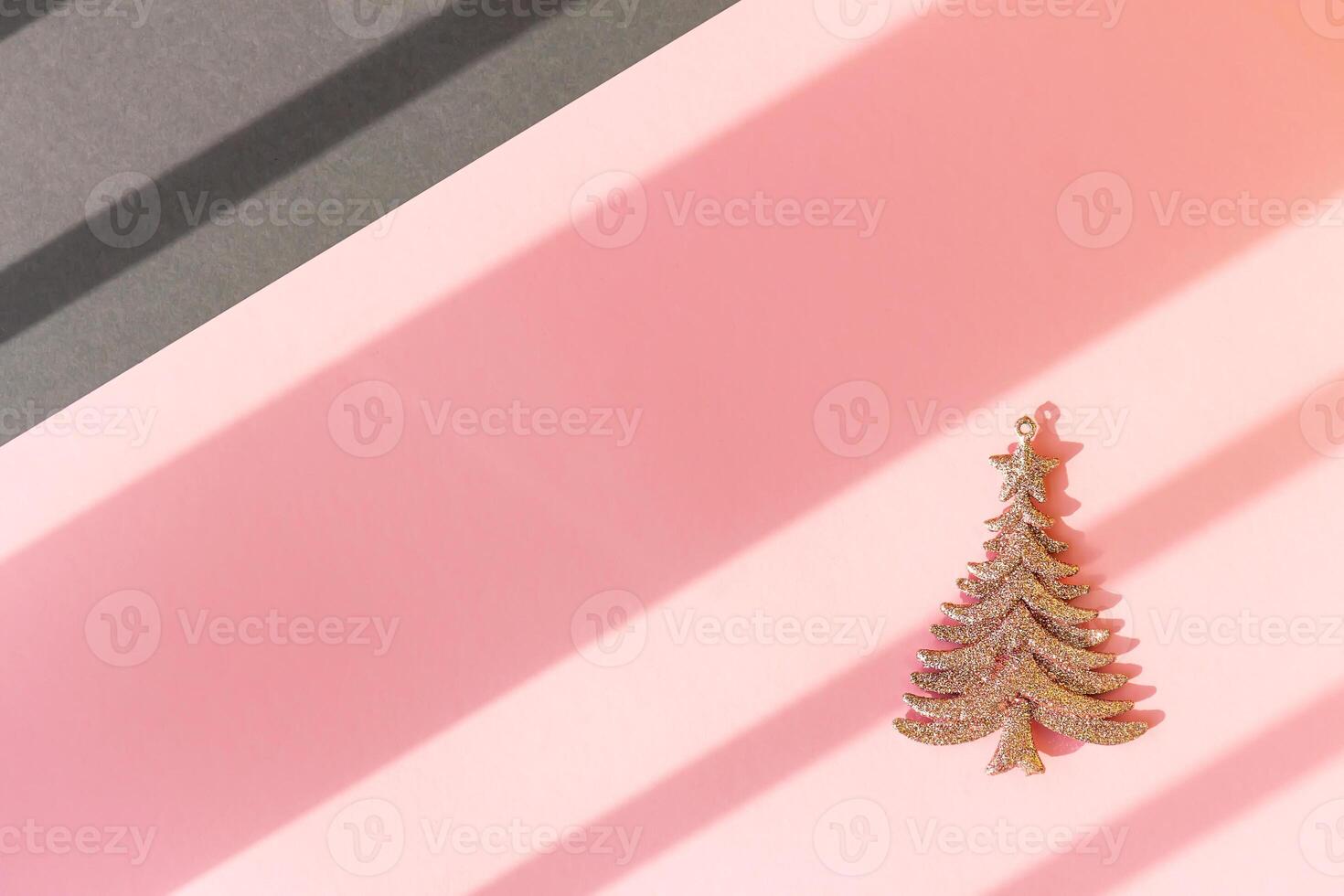 Christmas and New year shiny christmas tree on a pink and gray background with diagonal stripes from the rays of the sun photo
