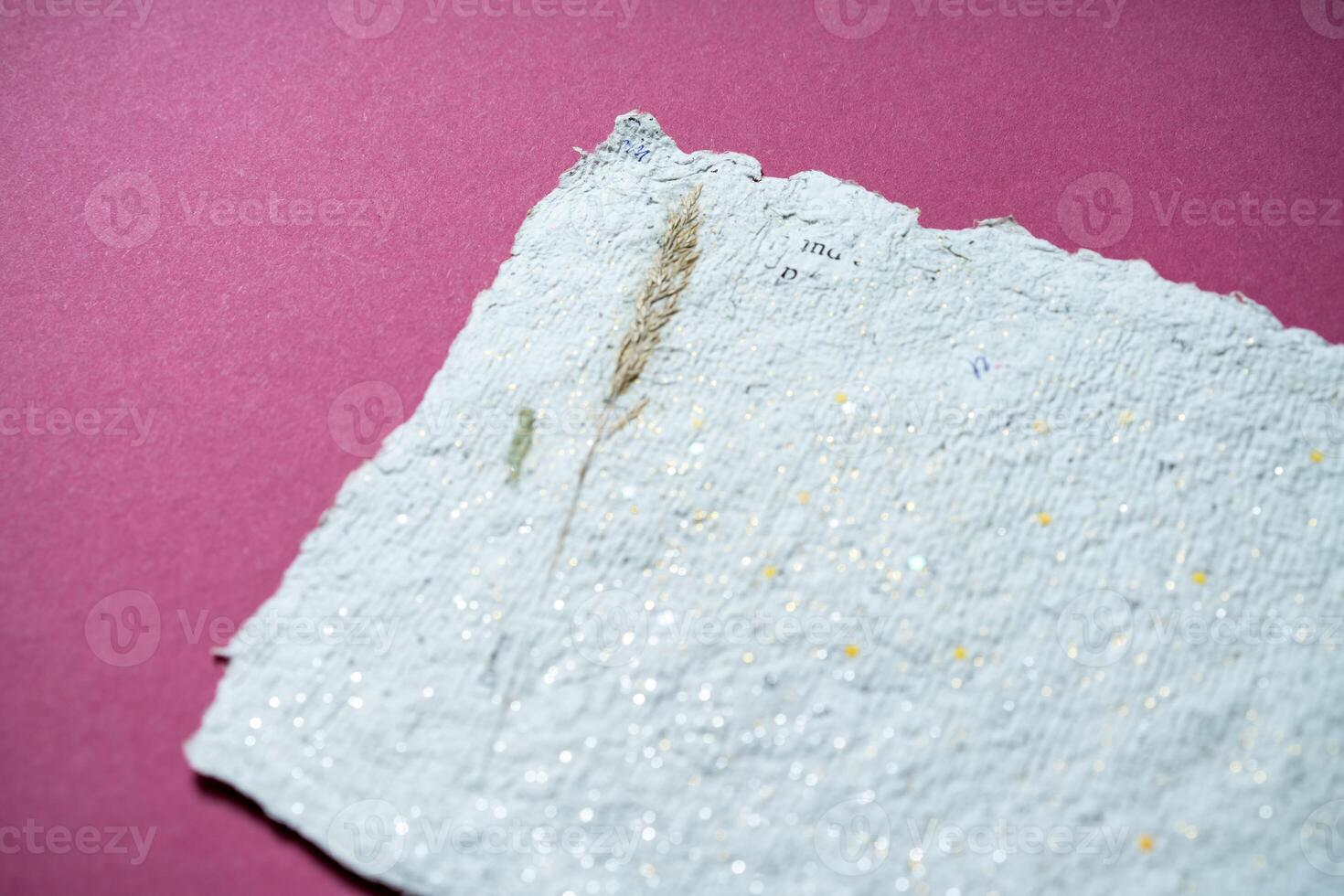 Sheets of recycled paper with dried flowers on pink background. Secondary production. Making paper with your own hands at home. photo