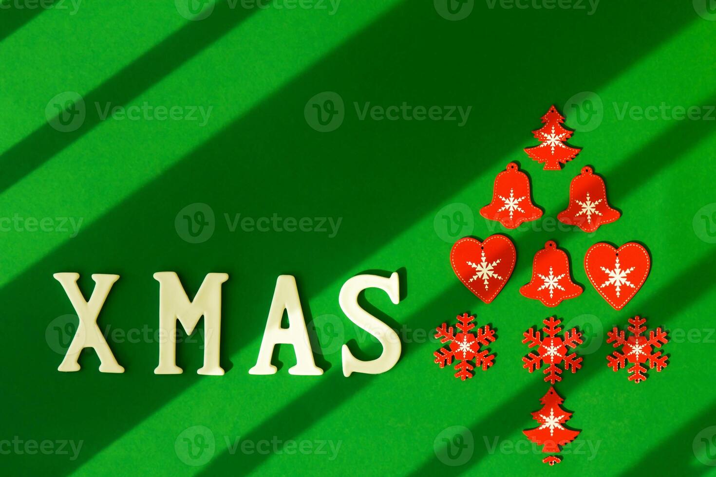 Red Christmas tree with inscription XMAS made of wooden Christmas tree toys on a green background with diagonal lines photo