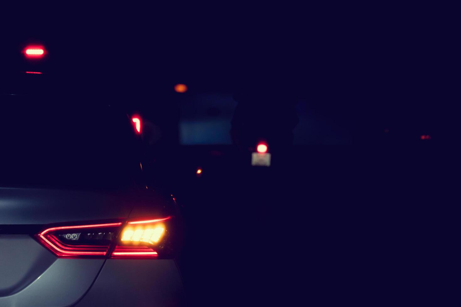 Abstract of rear side car on the road at night. Stop and turn on the right turn signal. Cars drive through a crosswalk at night. photo