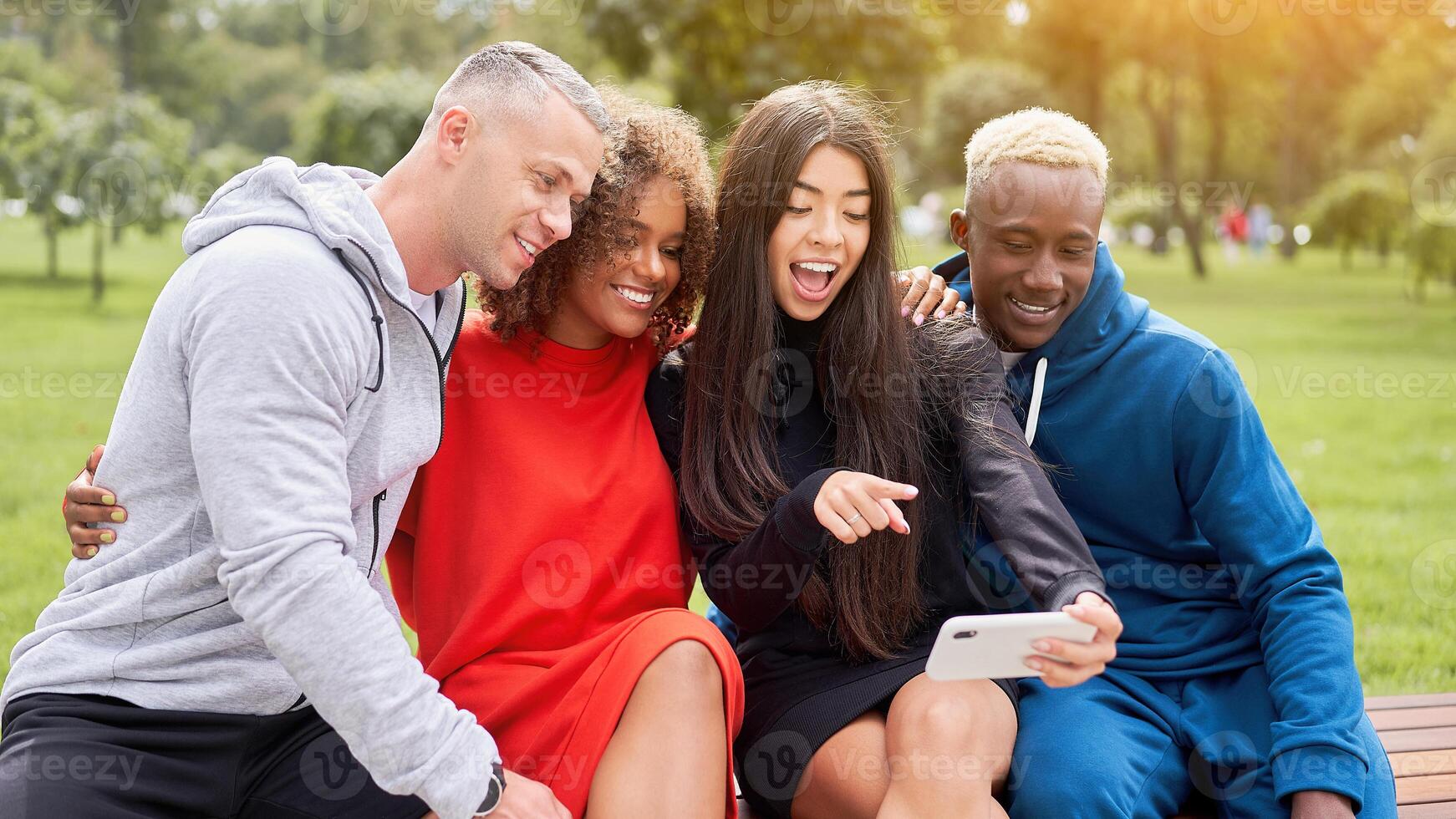Cheerful multiethnic friends taking selfie through smartphone in park photo