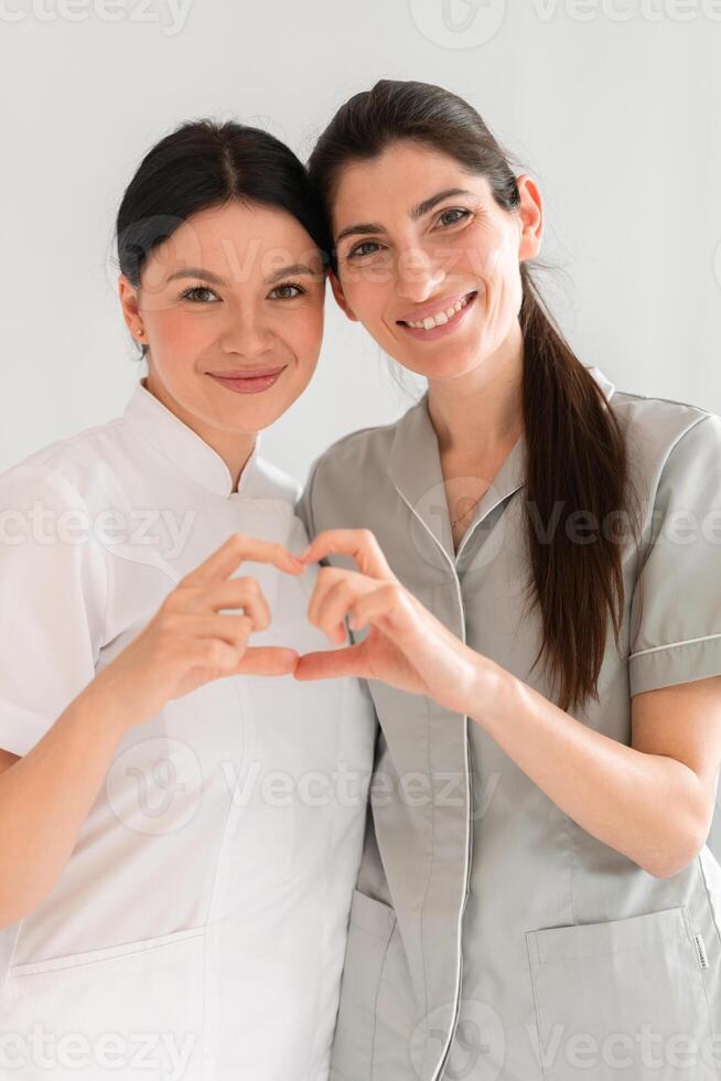 Happy female doctors making heart shape with hands at clinic photo