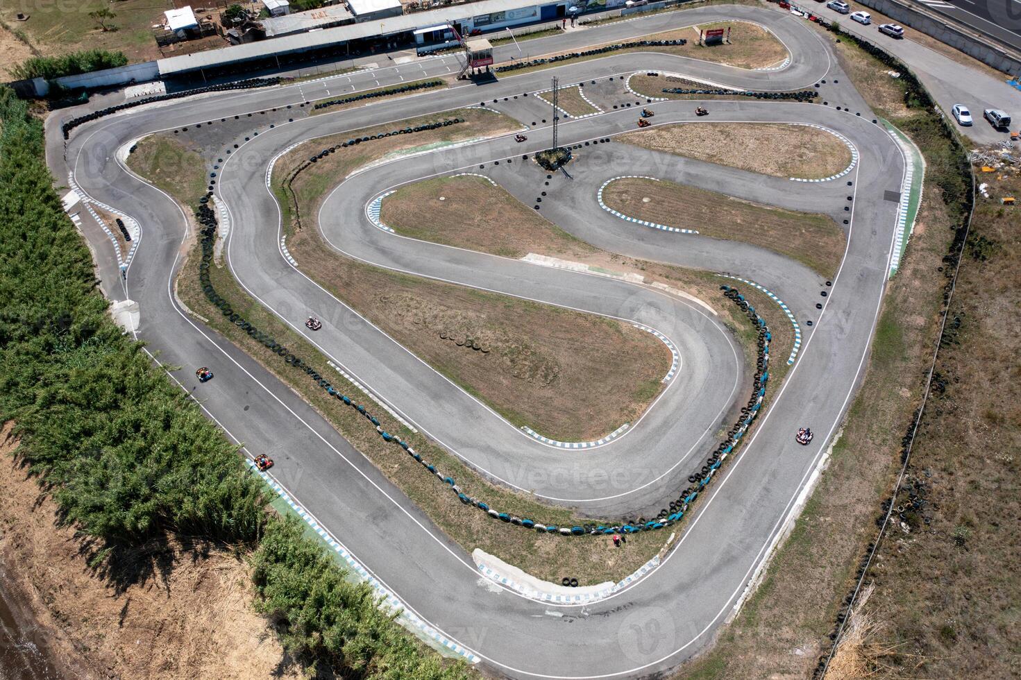 Drone rotating over go-karts racing on winding tracks from aerial view photo
