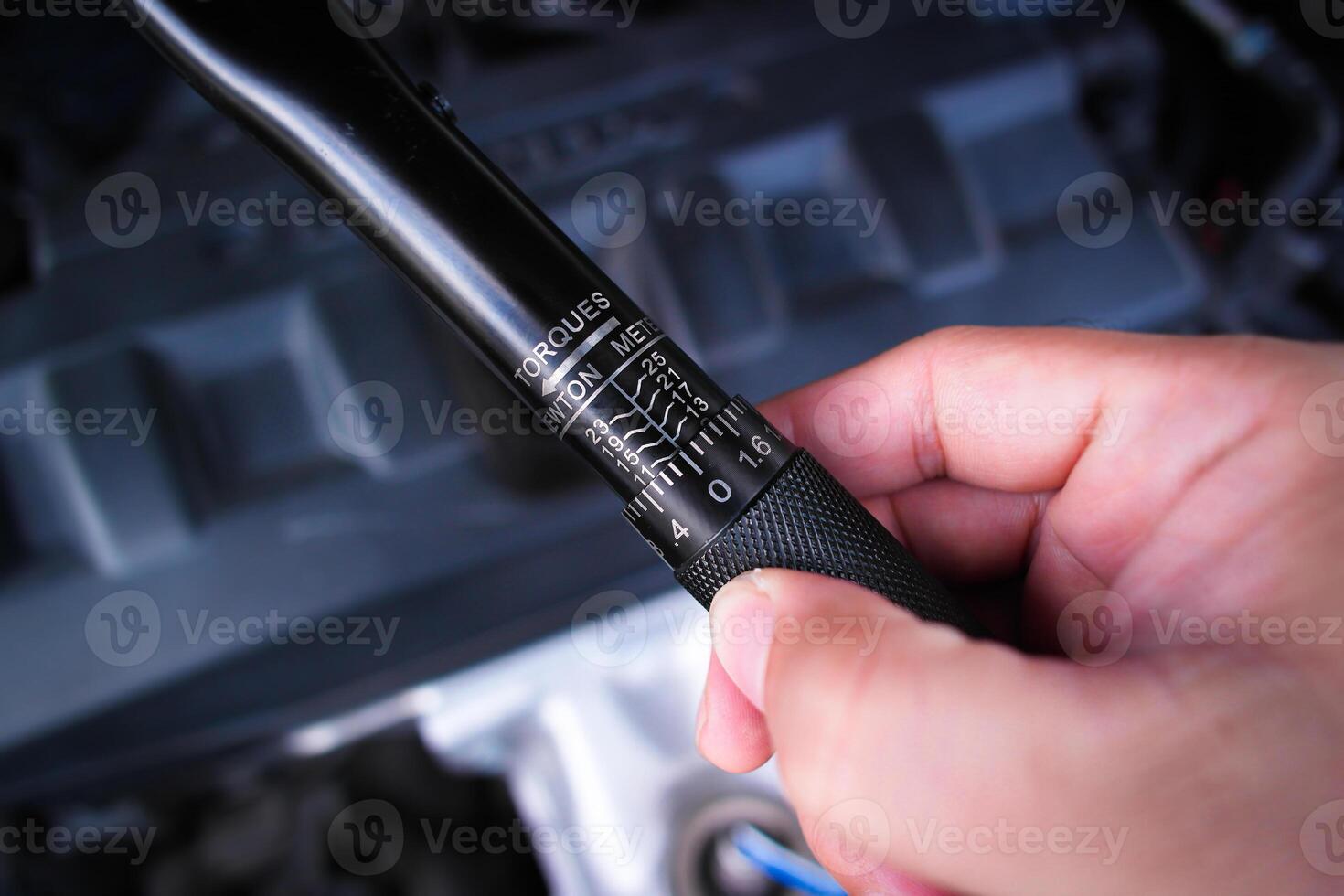 Close up of the torque wrench adjuster in a hand over car engine , Car mechanic tools concept photo