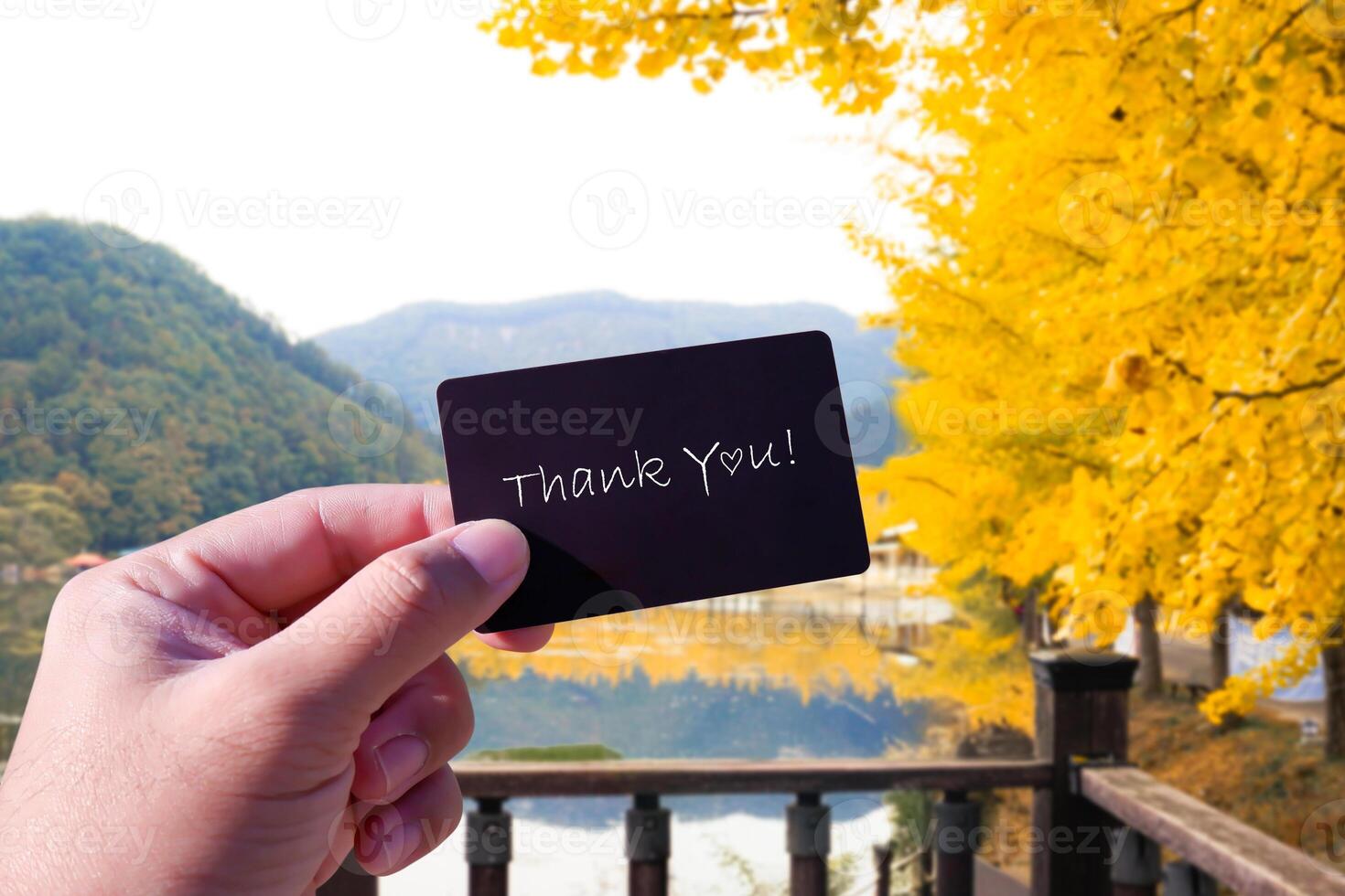 Thank You card in a hand against autumn landscape photo