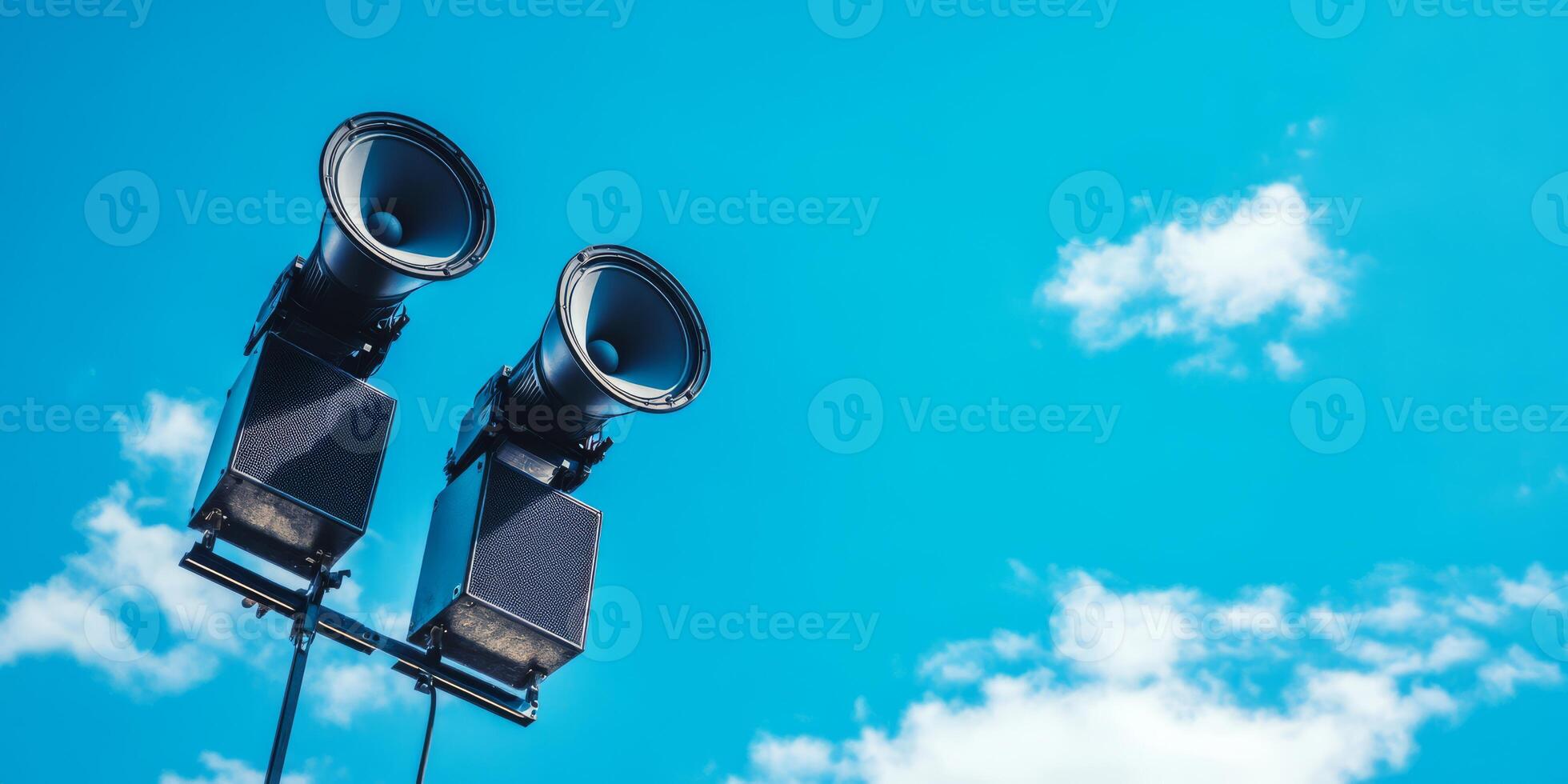 A pair of loudspeakers is mounted high on a sturdy pole against a clear blue sky, serving as an essential communication tool for public safety alerts and important announcements in urban areas photo