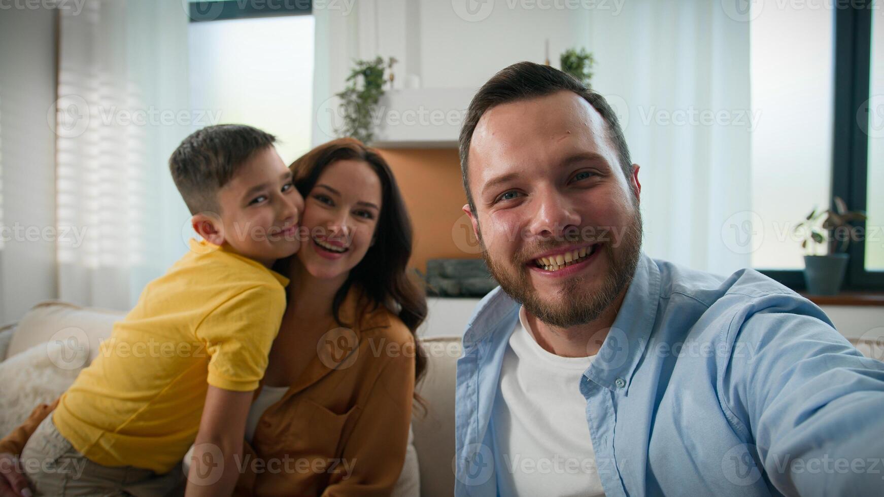 Happy Caucasian family talking on online call wave hello greeting looking at webcam father mother son bloggers recording vlog parents kid boy child communicate together remote on device at home photo
