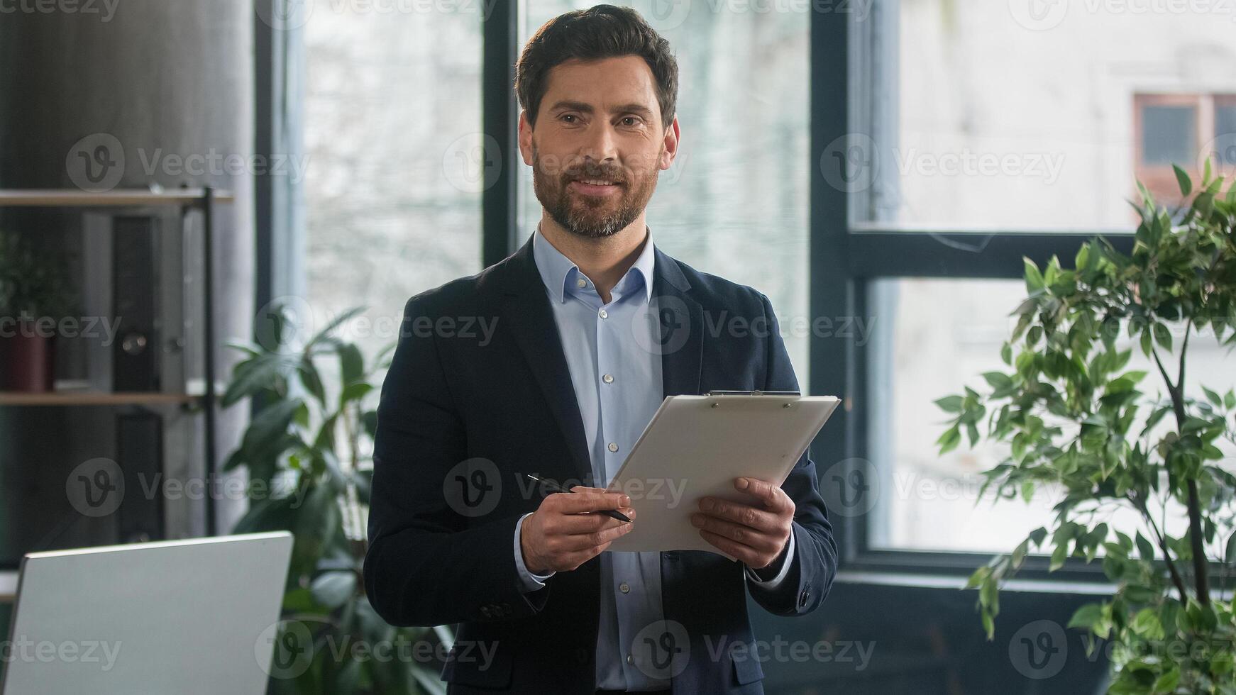 Focused adult caucasian man recruiting agent standing in office making notes writing checklist businessman conducts inspection write strategic plan showing thumb up gesture approval best choice sign photo