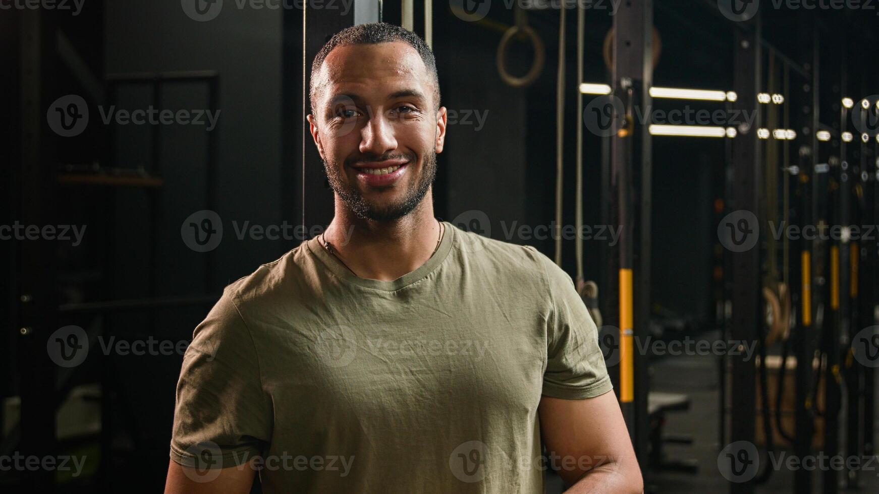 Strong muscular smiling personal fitness trainer guy African American man sportsman athlete bodybuilder boxer runner jogger posing in sport club gym instructor smile healthy sports workout exercise photo