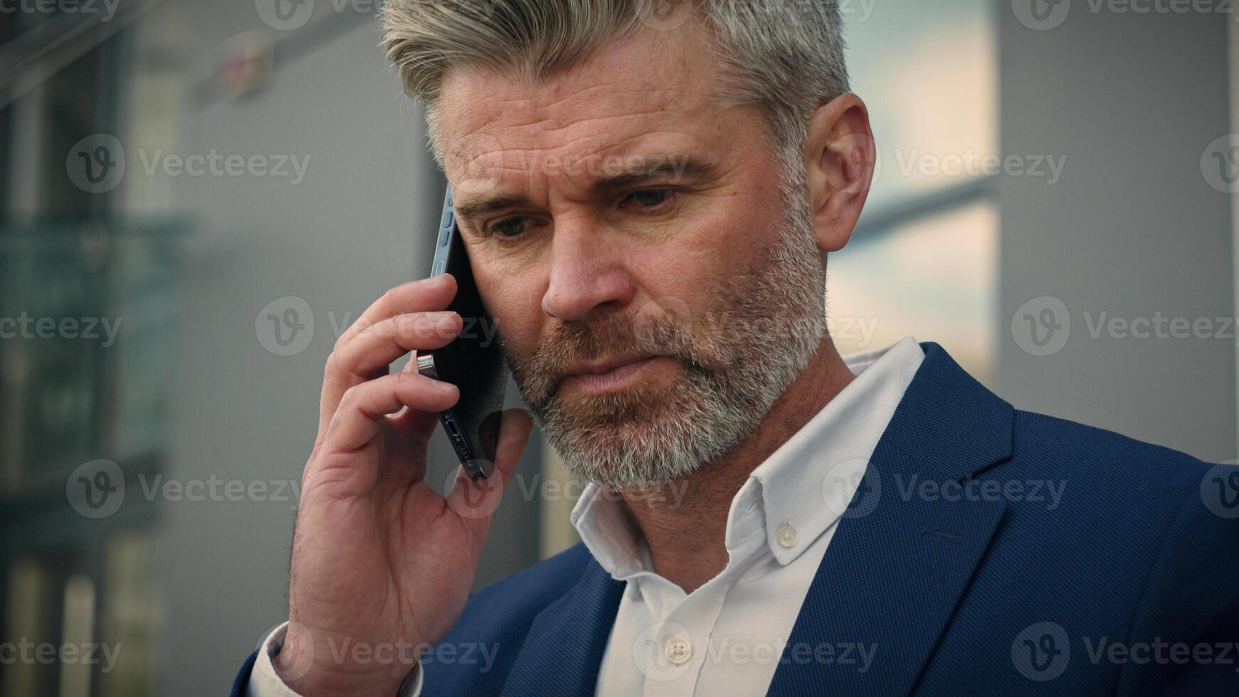 Caucasian old retired business man mature senior businessman leader employer talking mobile smartphone put on glasses end finish call putting phone in formal jacket pocket get up from bench walk away photo