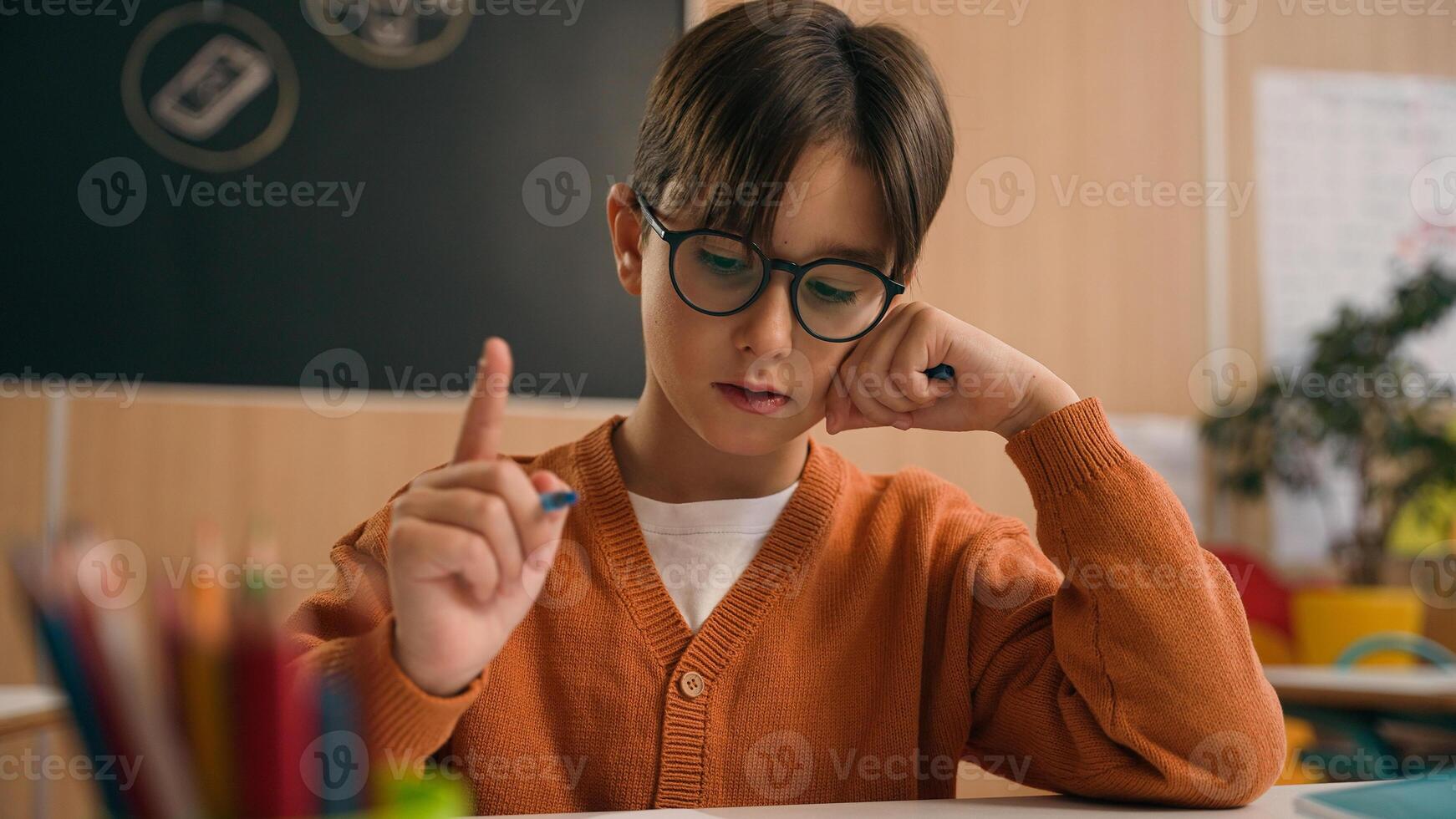 Caucasian guy boy think find idea ponder difficult task writing notes math exercise class lesson school learn write copybook kid schoolboy child pupil thinking studying primary education rise finger photo
