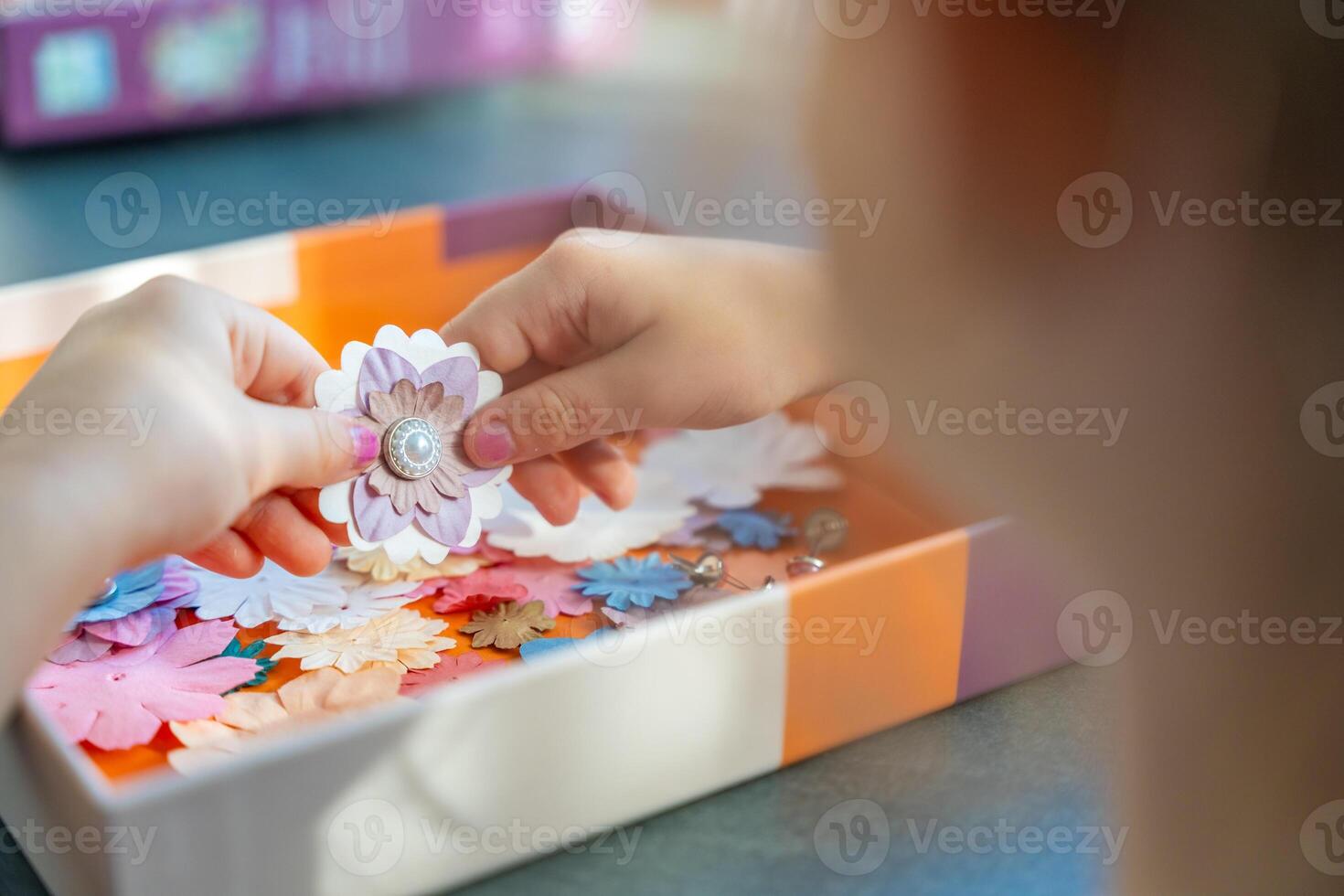 Small, colorful paper flowers in child hands, little girl creativing of 3D flowers. Child development toy. High quality photo