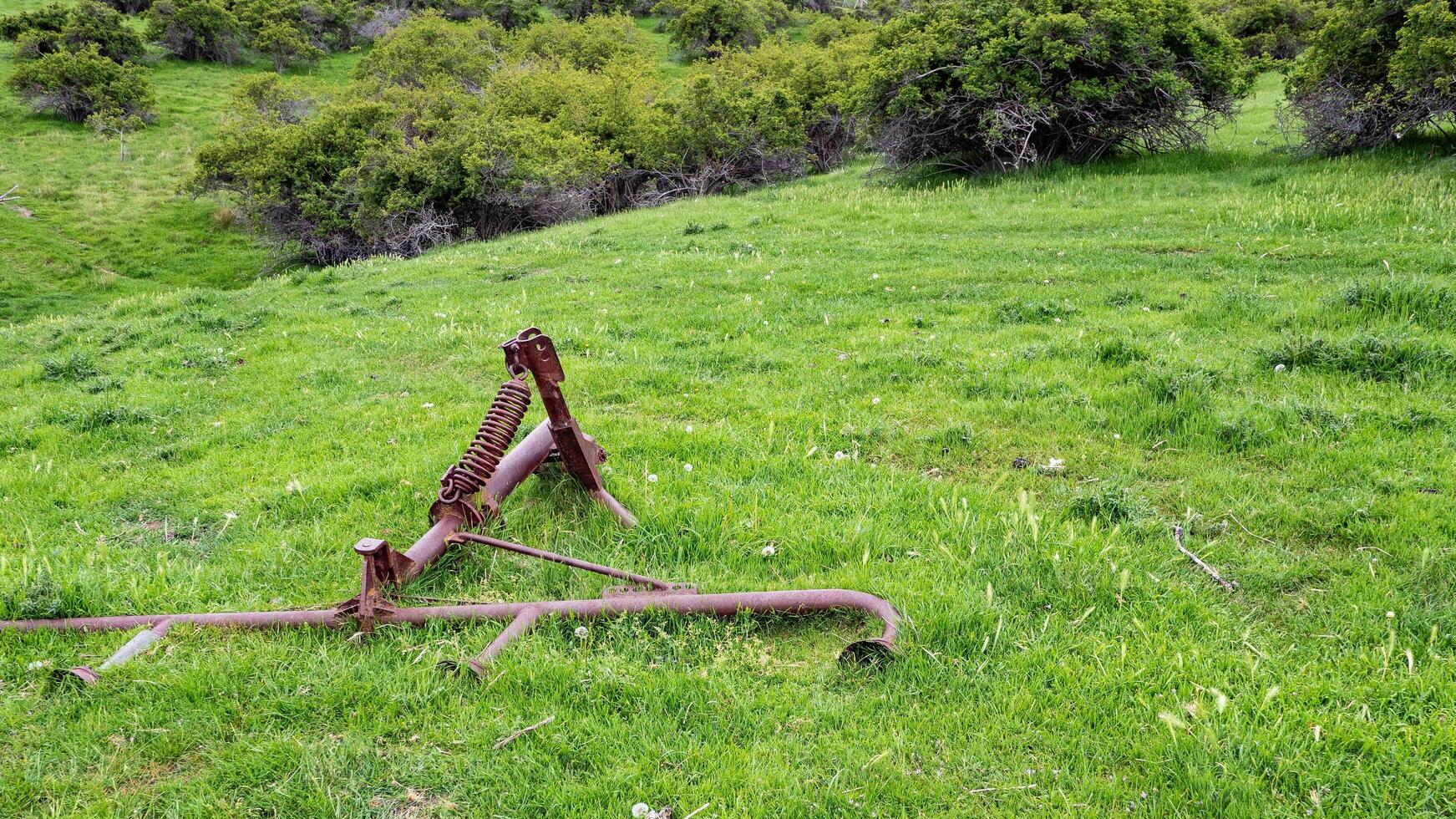 Old farm rusty equipment plow lying in grass old abandoned photo