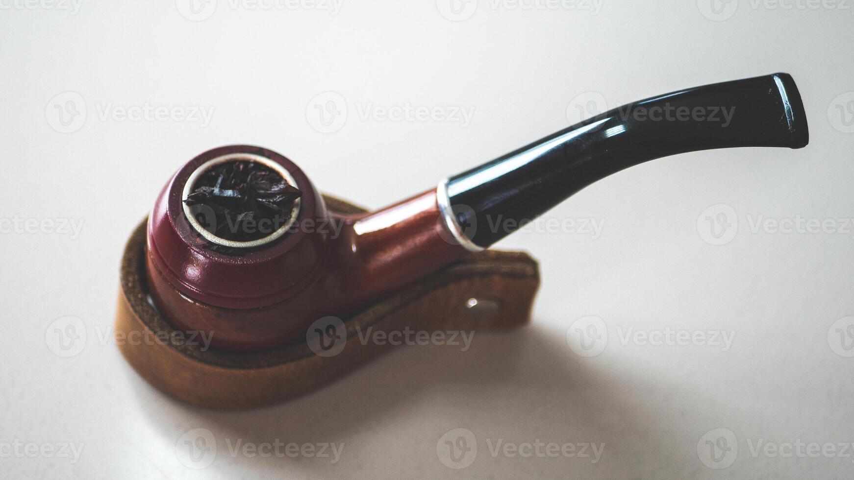 A smoking vintage pipe on a leather holder stand minimalist simple photo