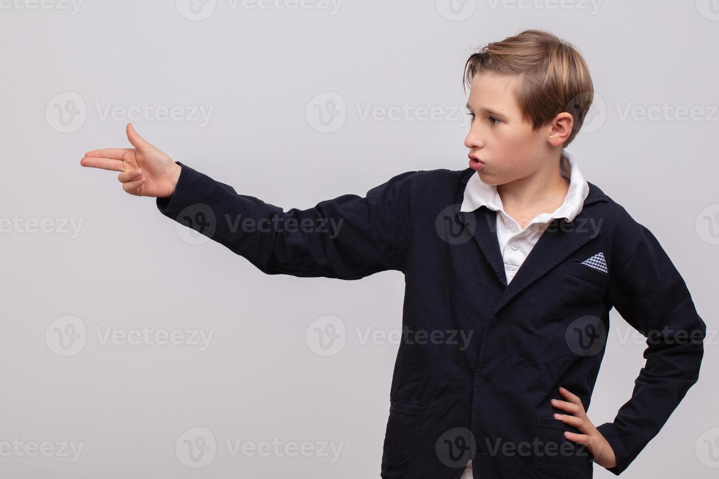 A schoolboy boy shows a gun gesture with his fingers. photo