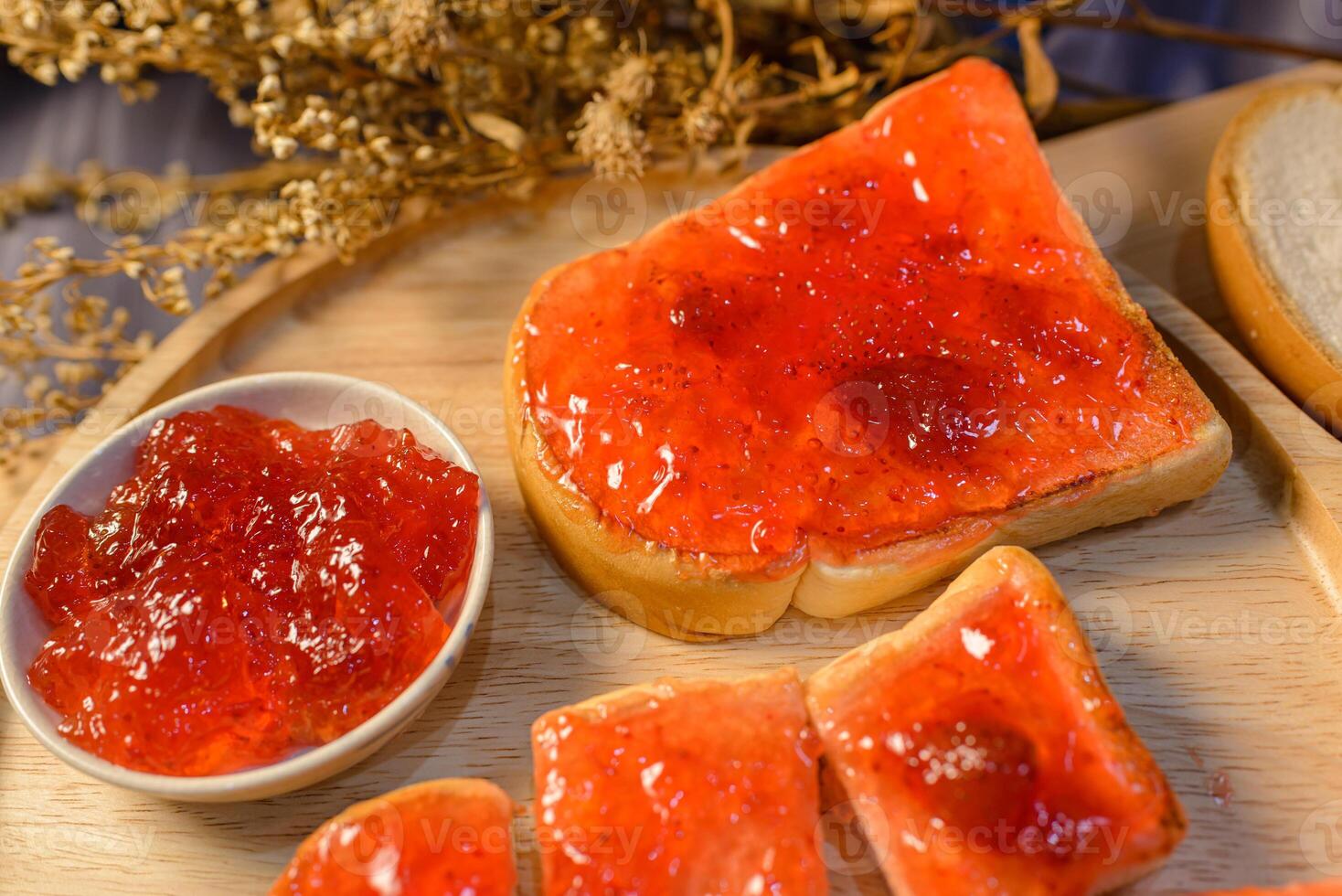 A slice of bread with jam on it and a bowl of jelly photo