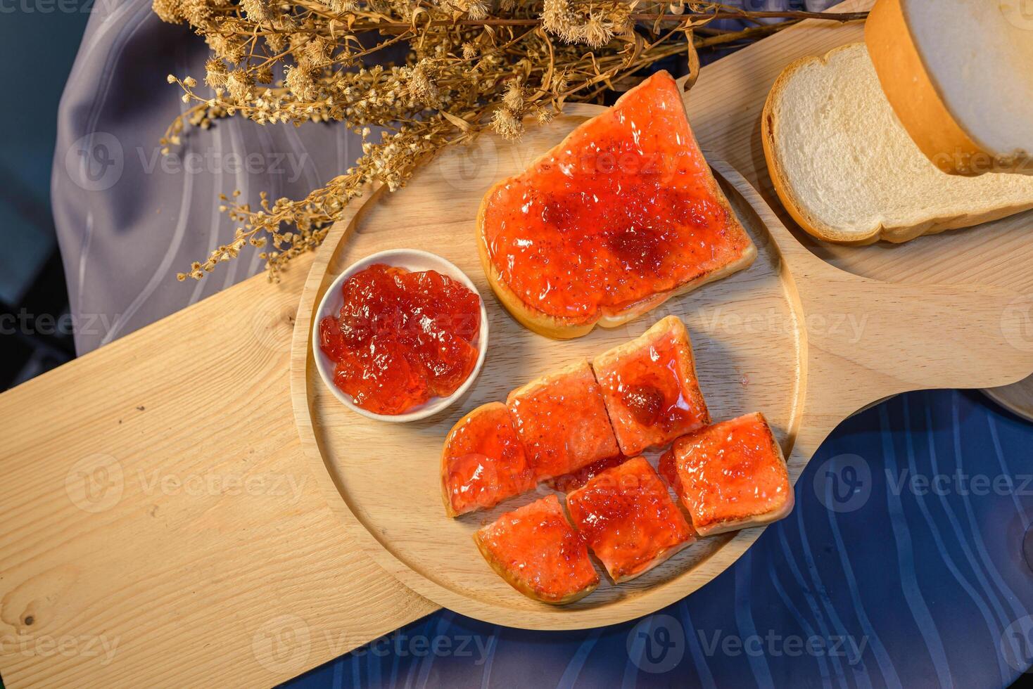 A wooden cutting board with sliced bread and jam photo