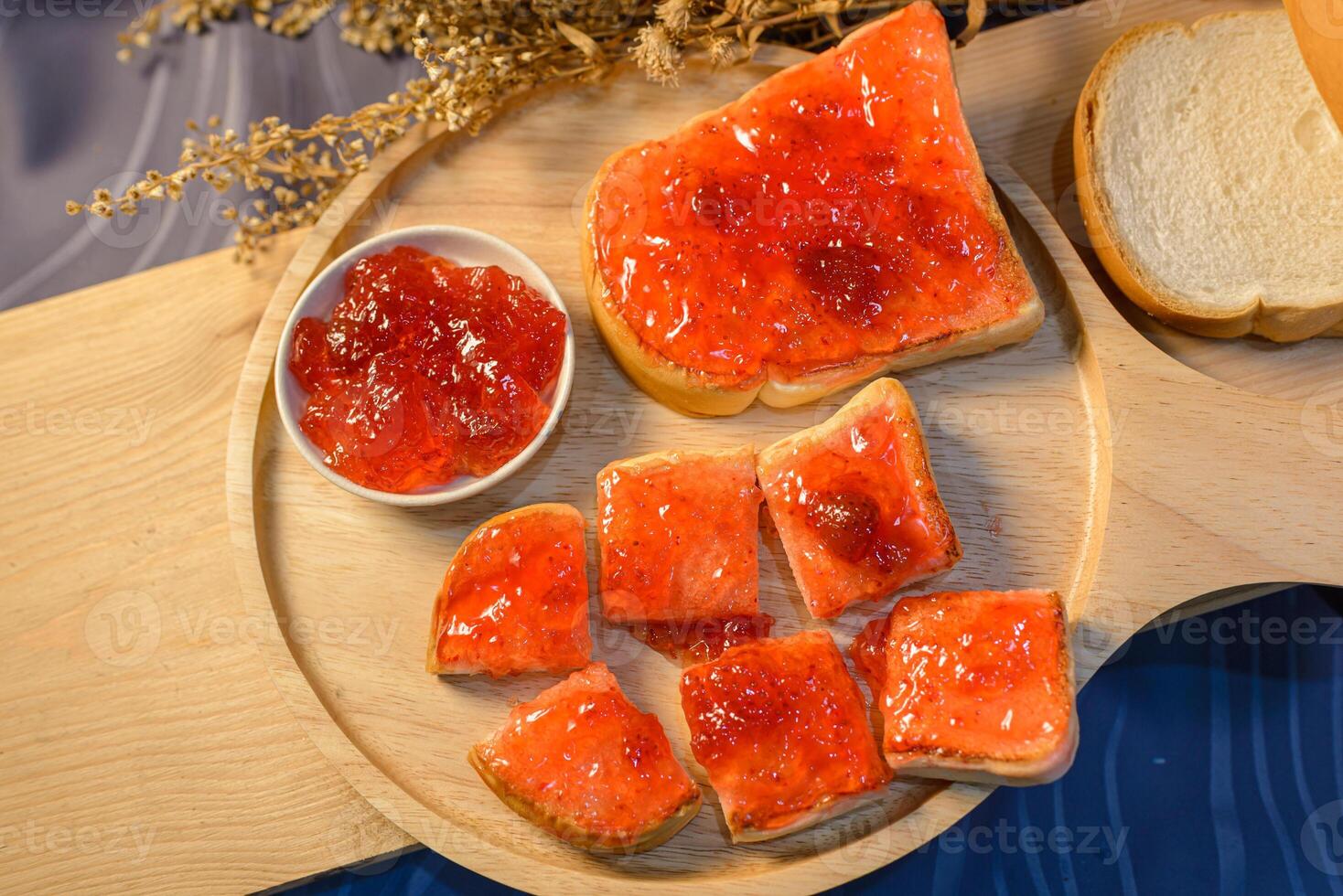 A wooden cutting board with bread and jelly photo